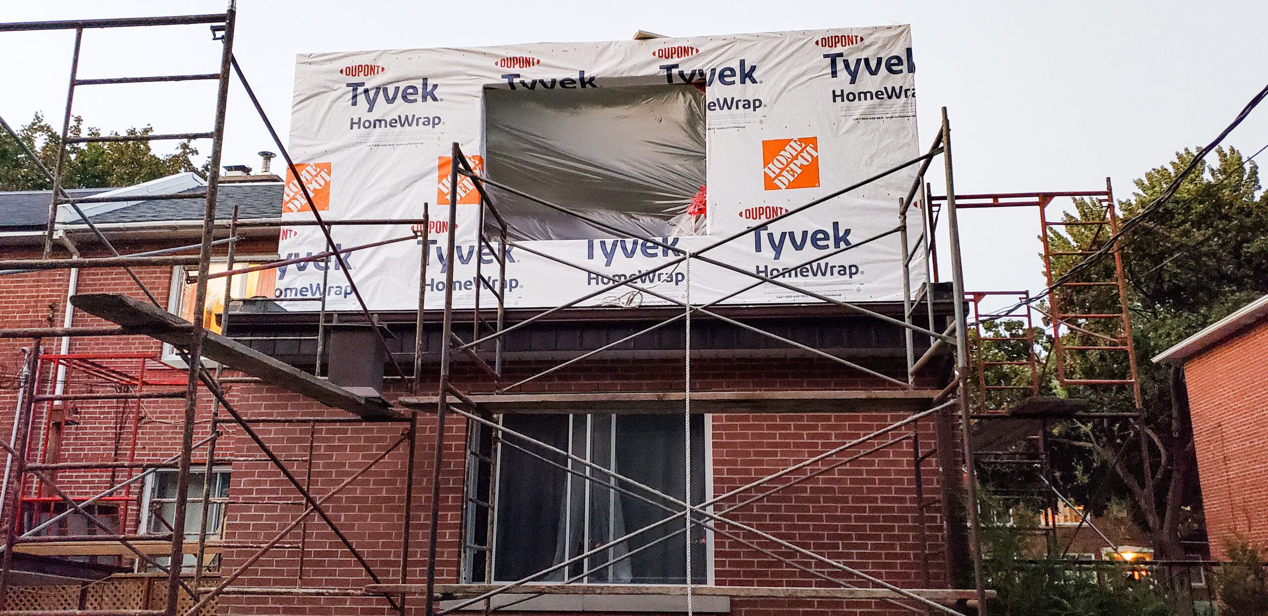Home & Building Additions Services Quebec representing a house covered with DuPont Tyvek HomeWrap during construction, that improve energy efficiency and weather protection for residential structures.