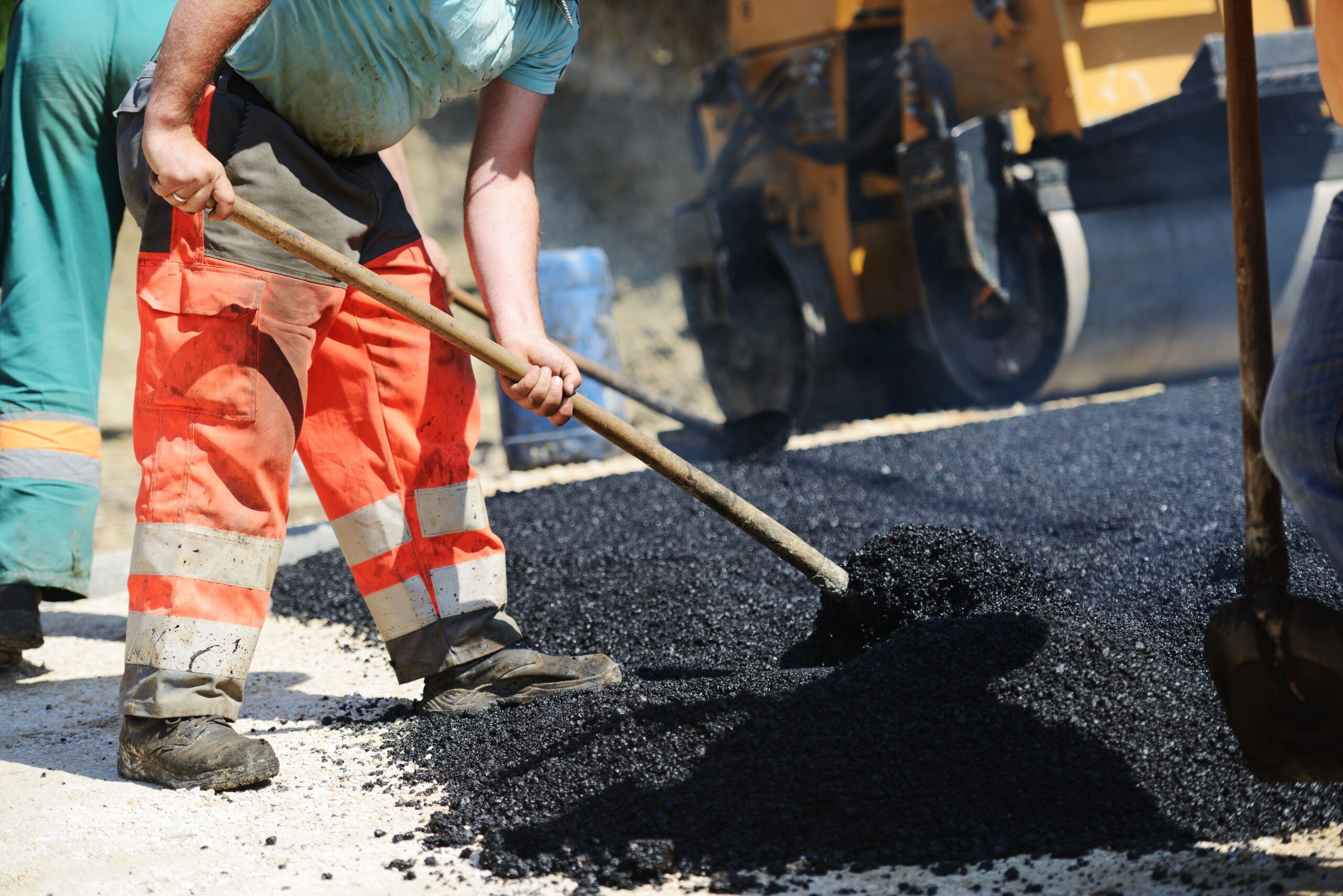 Paving Services in Quebec and Montreal showing road construction with hot asphalt being laid and compacted by a roller to create a smooth and durable surface.