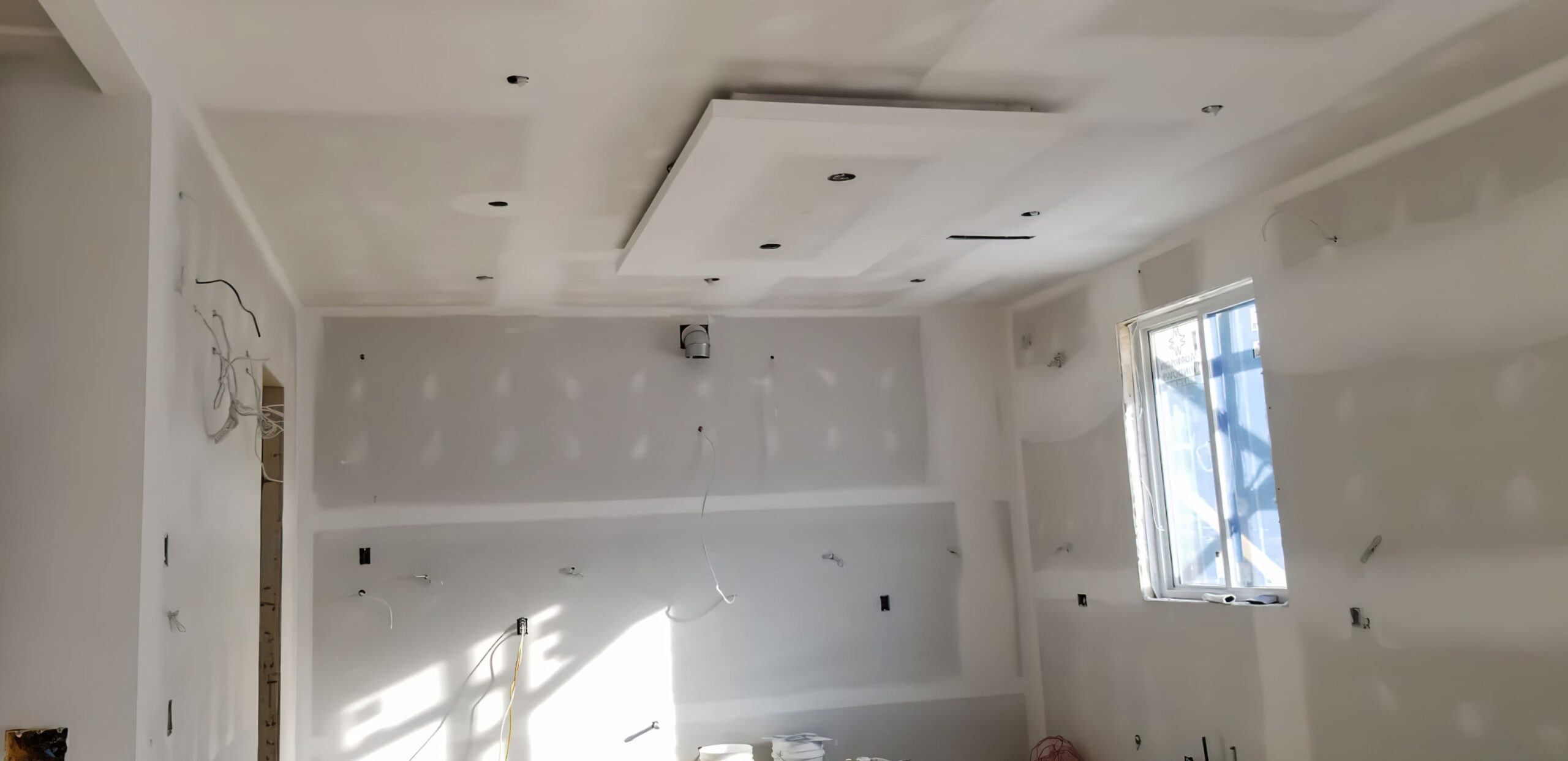 Interior construction site showing drywall installation with gypsum boards on metal framing, representing professional interior systems in Quebec for efficient and flexible wall and ceiling construction.