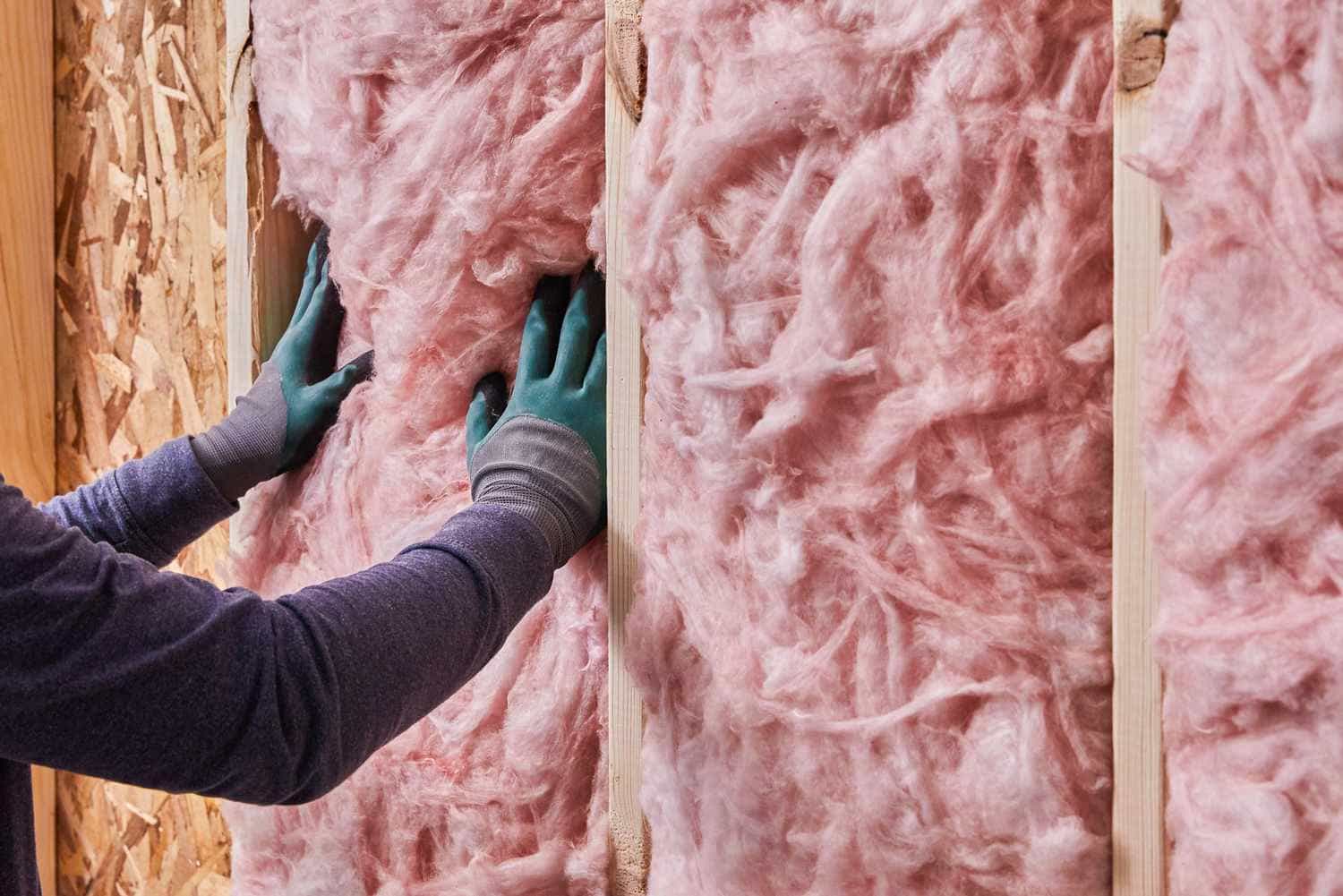 Installation of fiberglass insulation in a residential wall, showcasing professional insulation services in Quebec and Montreal that enhance thermal efficiency and noise reduction using recycled glass materials.