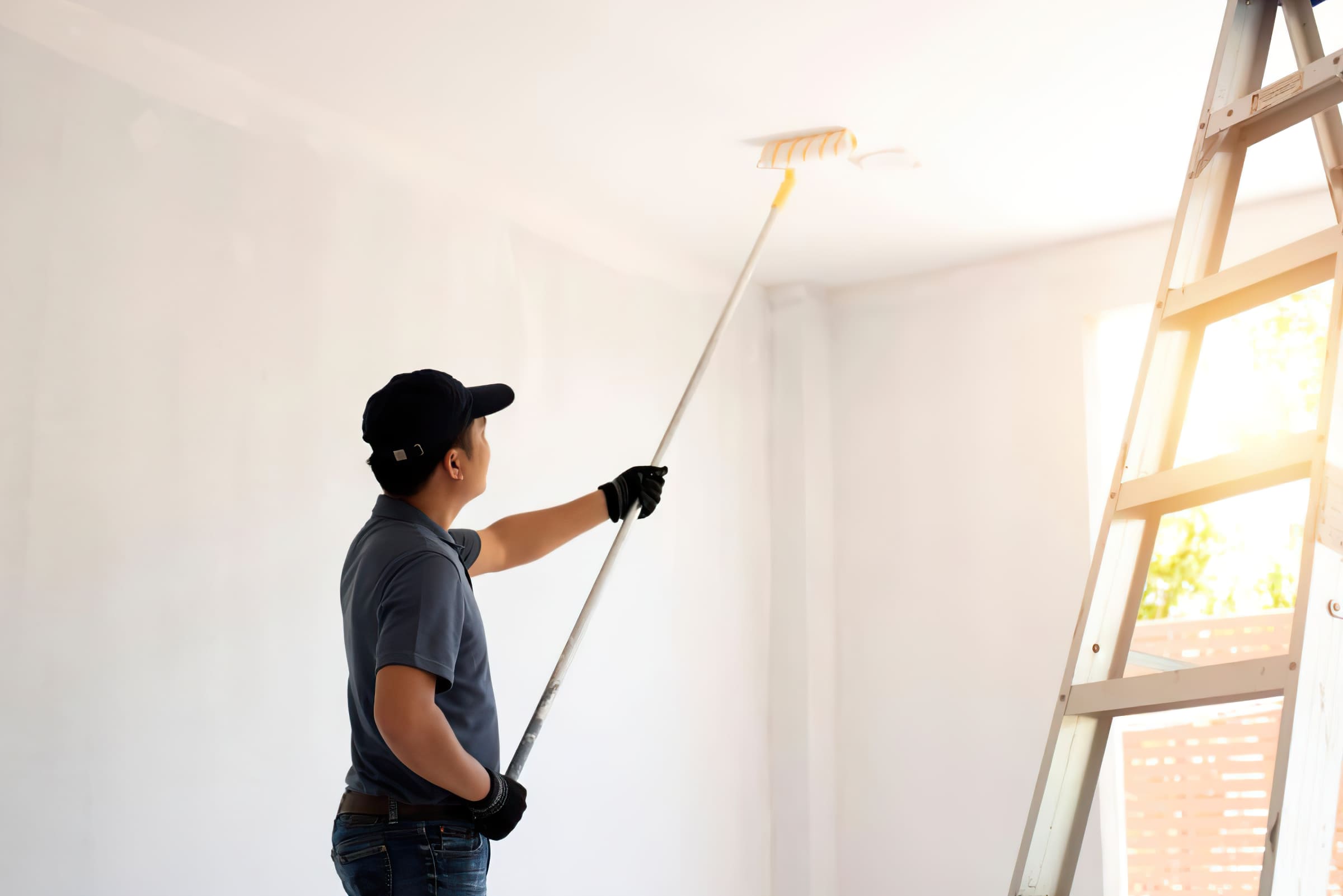 Painting services Montreal showing a painter applying matte ceiling paint with a roller, demonstrating professional ceiling painting techniques for residential and commercial interiors in Montreal.
