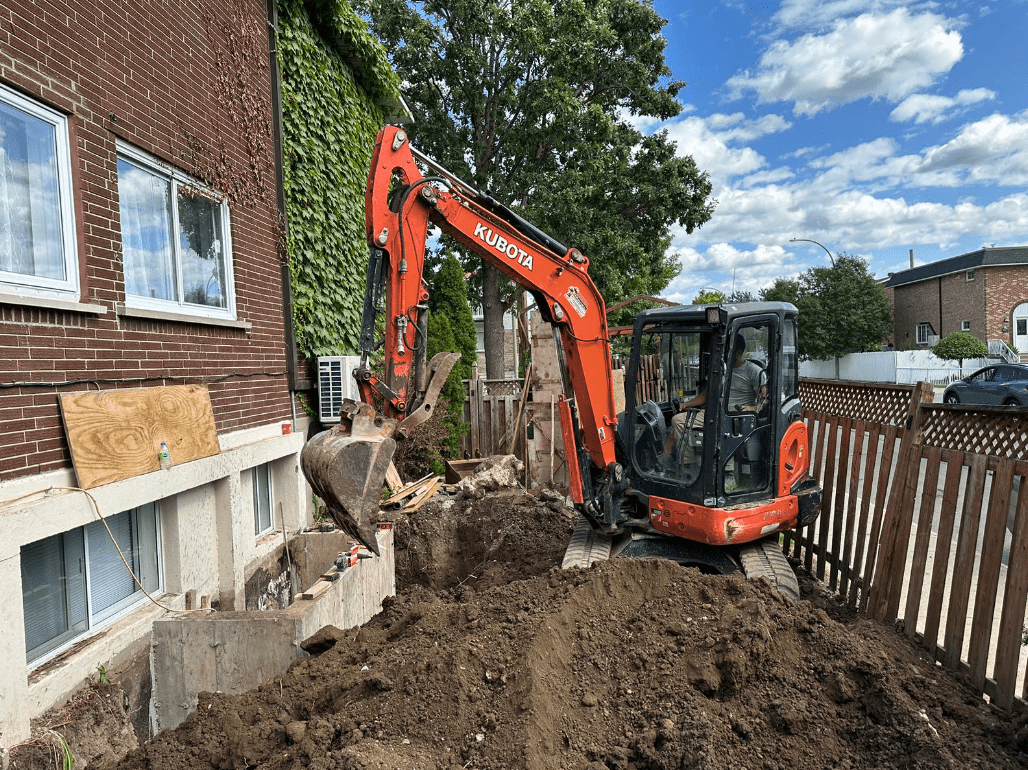 Kubota mini excavator working beside a building, a compact machine used for excavation and landscaping in tight areas, known for its reliability and fuel efficiency.
