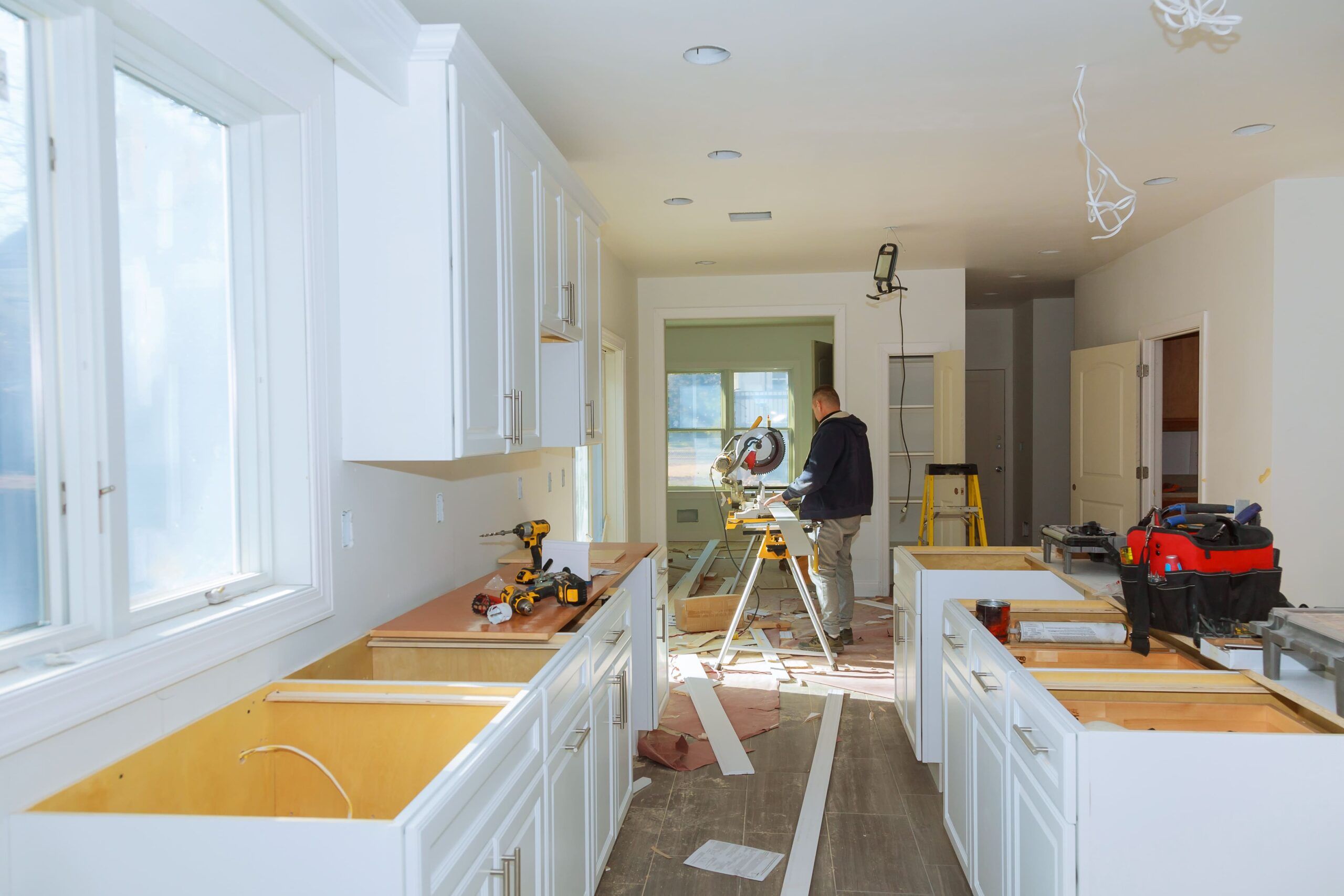 Contractor installing kitchen cabinets and countertops during a renovation, with tools visible on-site, representing expert kitchen design and remodeling in Quebec focused on modern functionality and style.