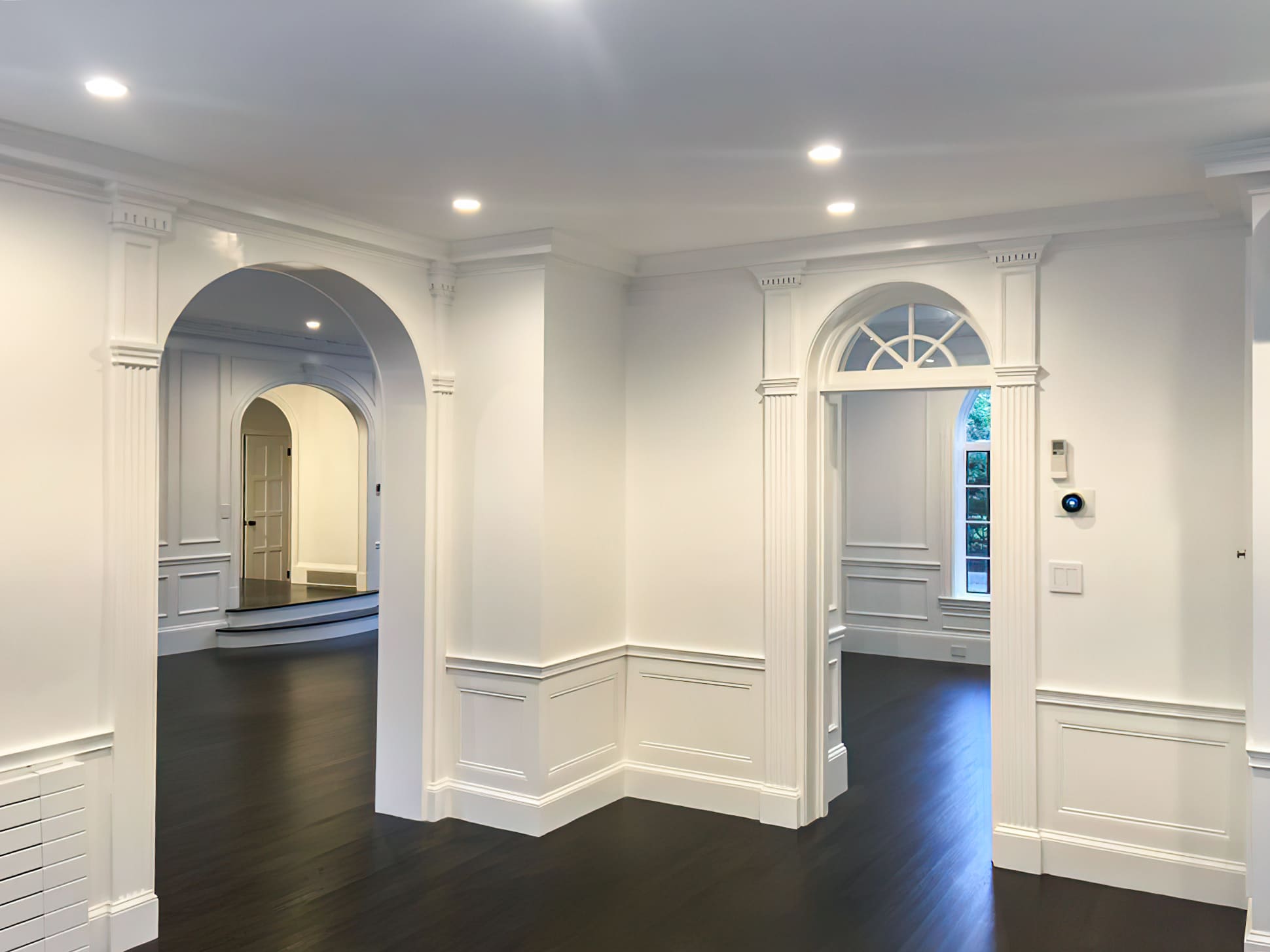 Interior painting Quebec – elegant room with white walls, multiple archways, and decorative moldings. Classic interior design highlighting detailed trim and arches, showing professional painting services in Quebec.