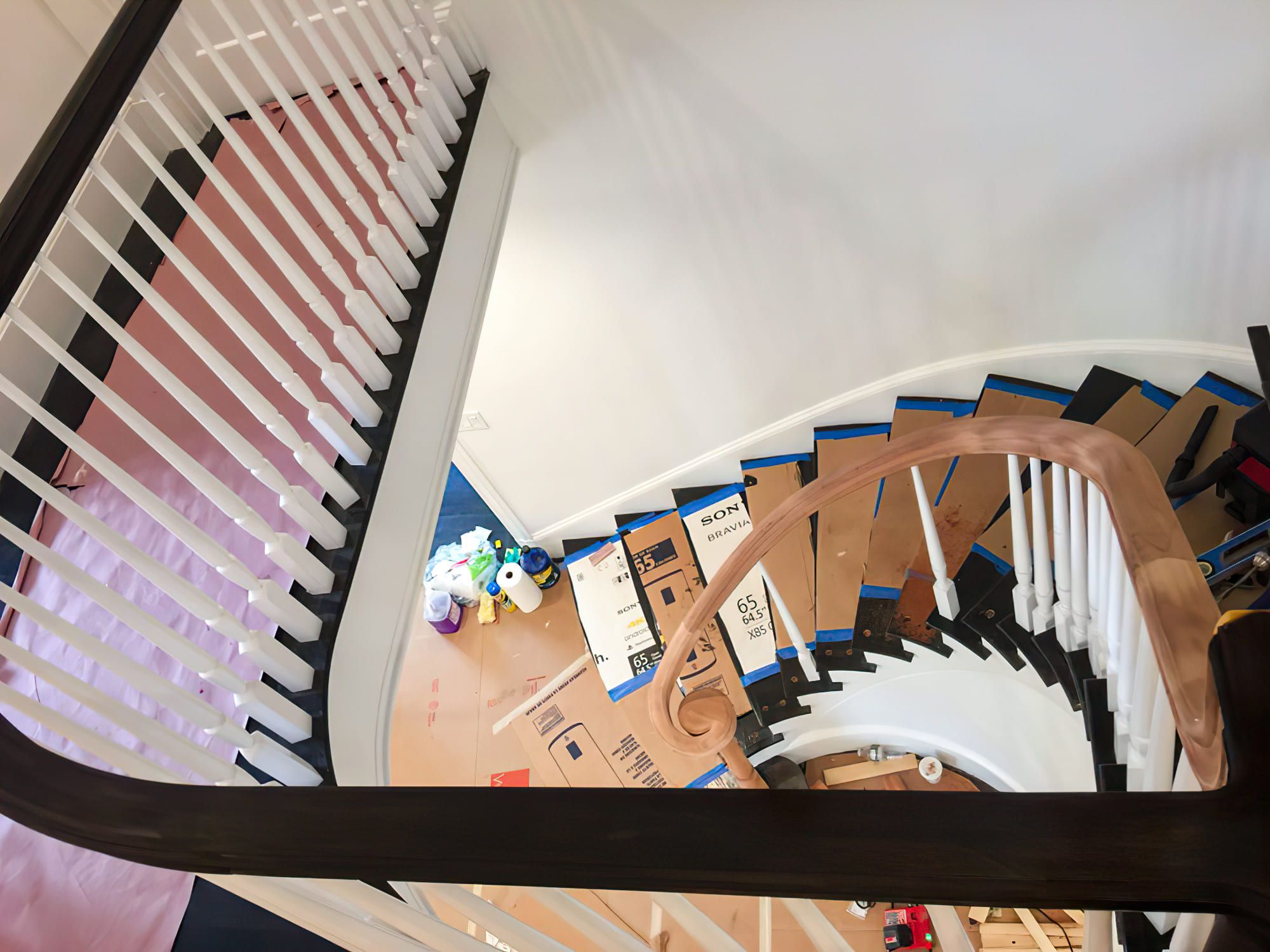 A modern spiral staircase winding upward in a residential interior. The staircase features narrow inner steps and an open central core, combining functionality with elegant design.