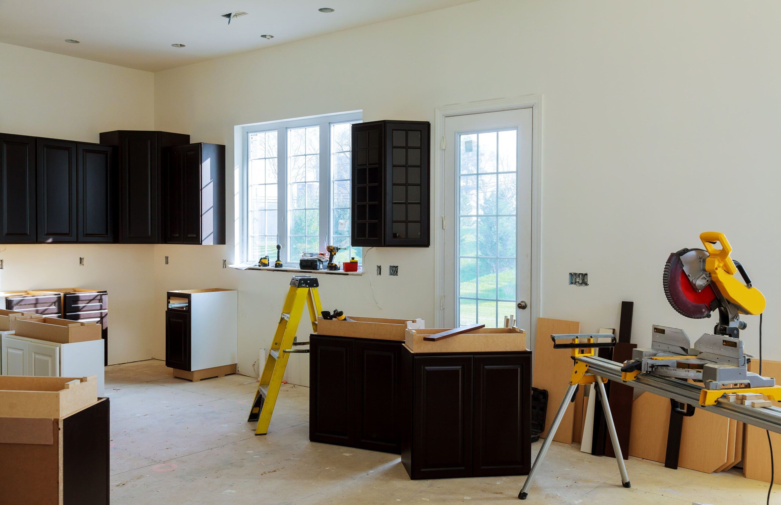Kitchen under renovation with black cabinets being installed, tools and materials on site, representing a residential kitchen upgrade in Quebec focused on modern design and functionality.