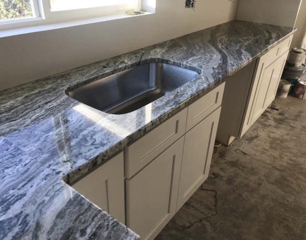 Polished granite kitchen countertop with integrated sink, showcasing elegant and durable materials used in kitchen design and remodeling in Quebec for modern and long-lasting interiors.
