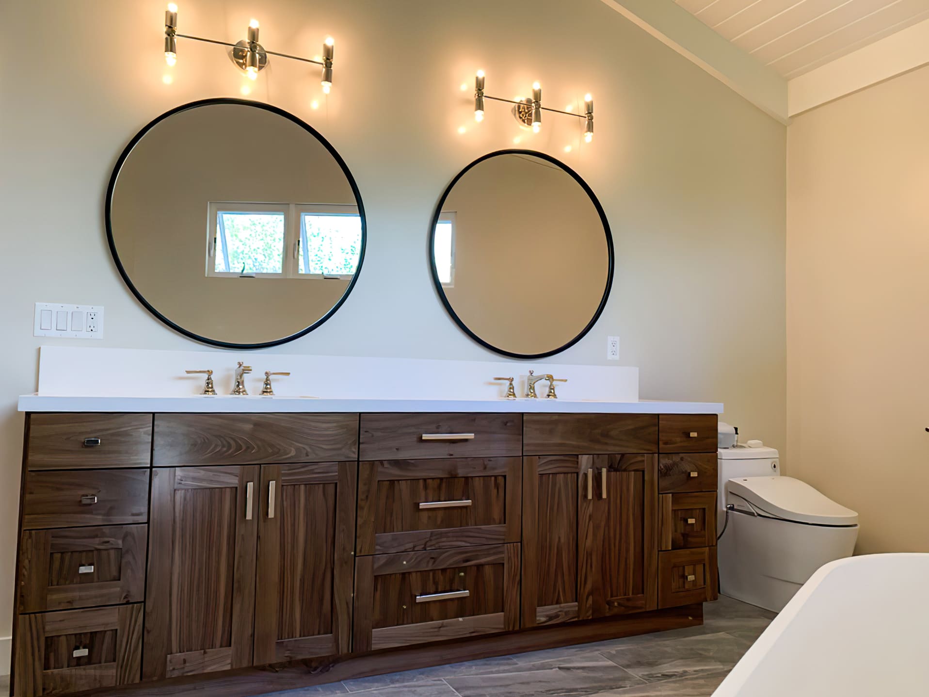 Double wooden vanity with white countertop and two round mirrors, showcasing stylish and functional bathroom design and remodeling in Quebec.