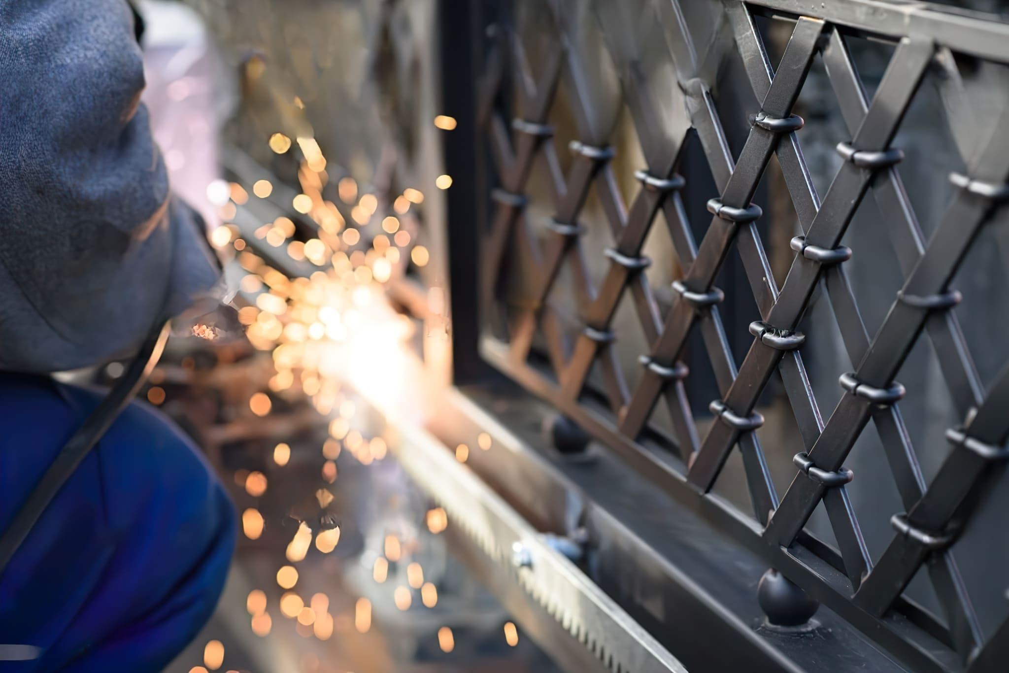 welder working with protective gear — the image shows a person performing welding, a joining process where metals are fused using intense heat; as the molten metal cools, it forms a strong bond; the welder wears full personal protective equipment, including a helmet and gloves, to shield against sparks, heat, and UV radiation; various welding methods such as MIG, TIG, and arc welding are commonly used in metal fabrication and construction.