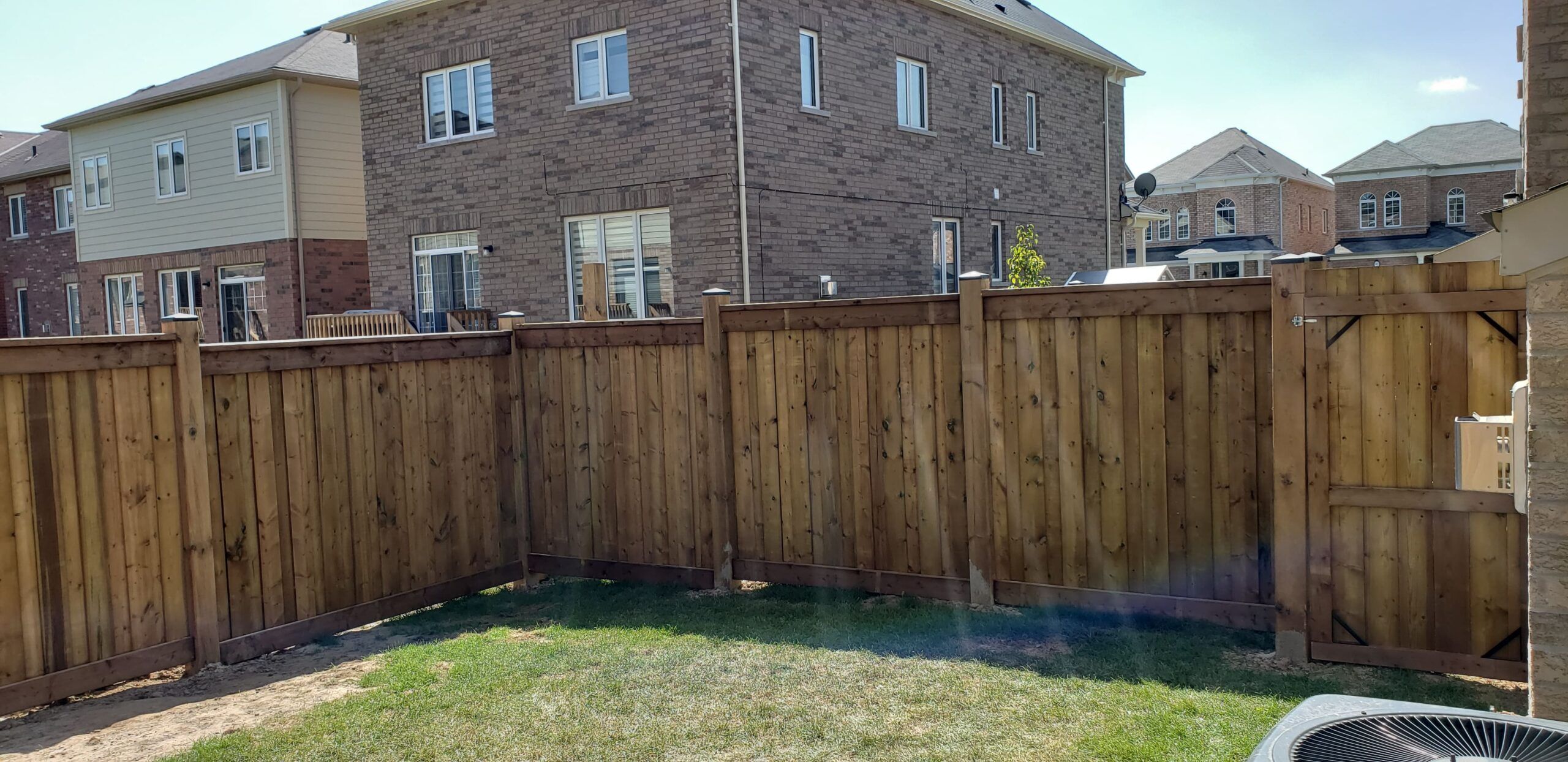 A wooden privacy fence surrounding a garden, built with overlapping vertical boards and sturdy posts to enhance privacy and reduce noise, showcasing the natural charm and practicality of garden fences in Quebec.