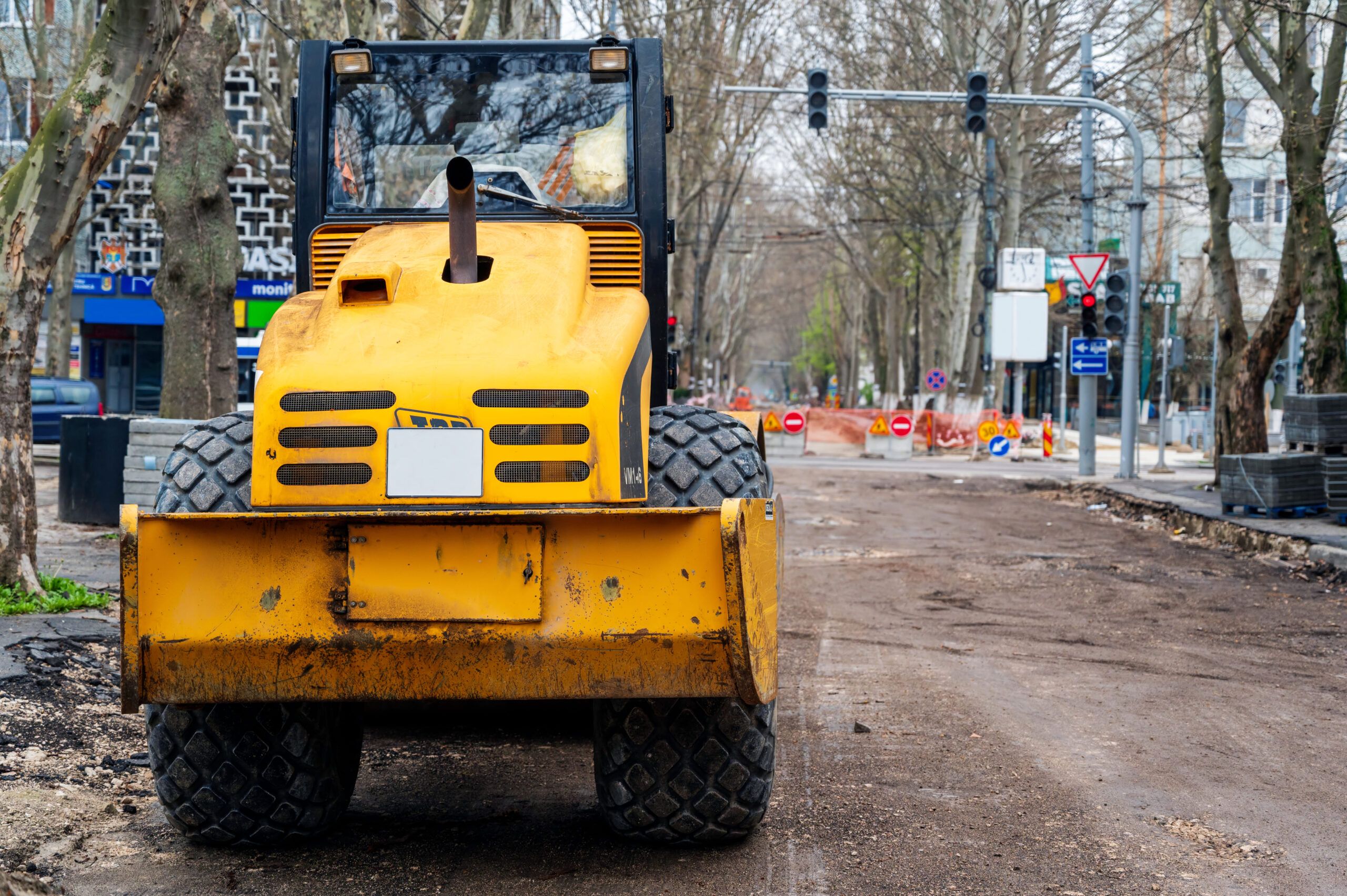 Paving Services in Quebec with a yellow JCB VM146 road roller working on a street construction site, compacting asphalt for a newly paved roadway.