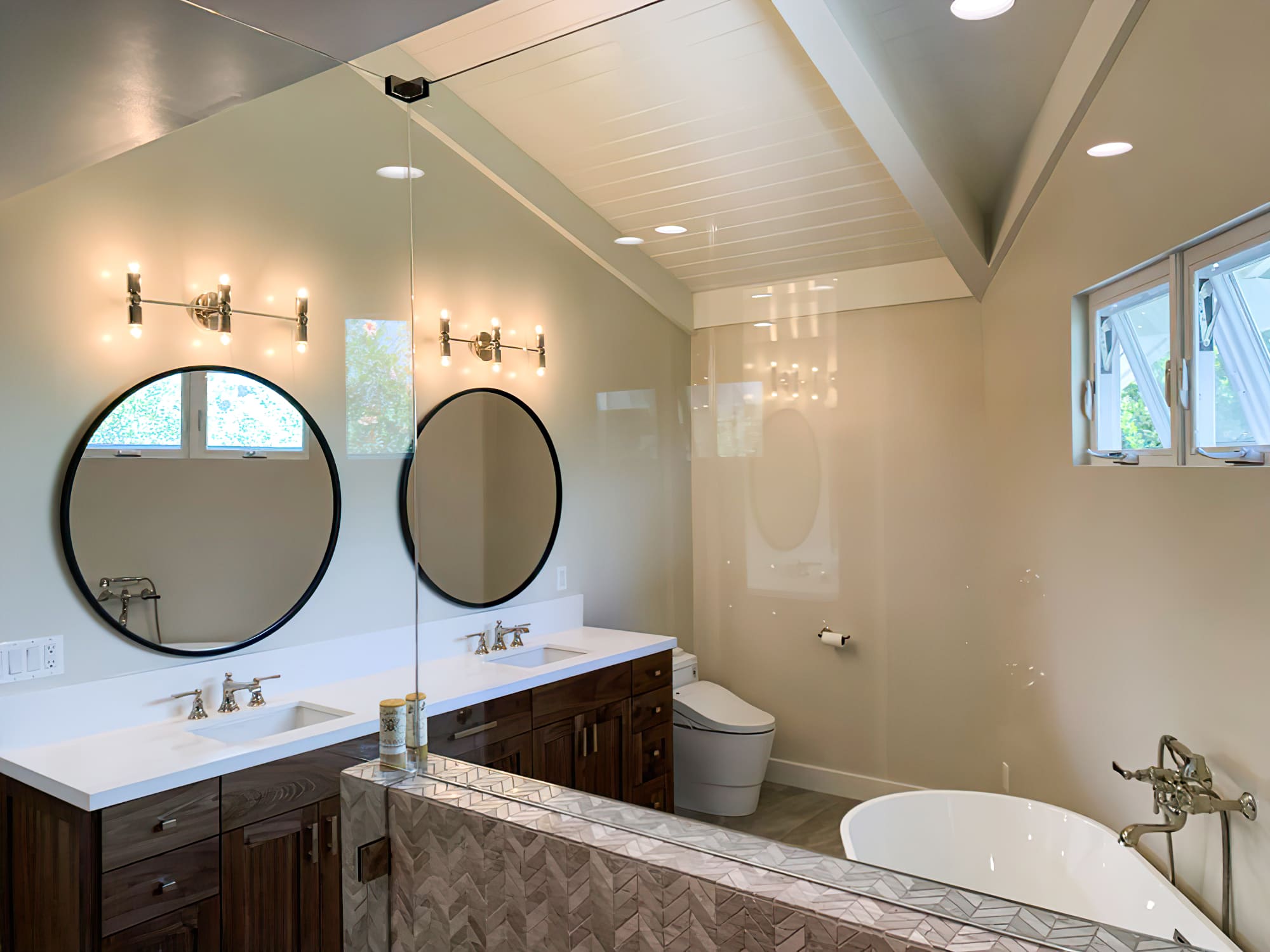 Modern bathroom with double vanity, round mirrors, freestanding tub, glass shower, and accent wall, showcasing elegant bathroom design and remodeling in Quebec with contemporary lighting and finishes.