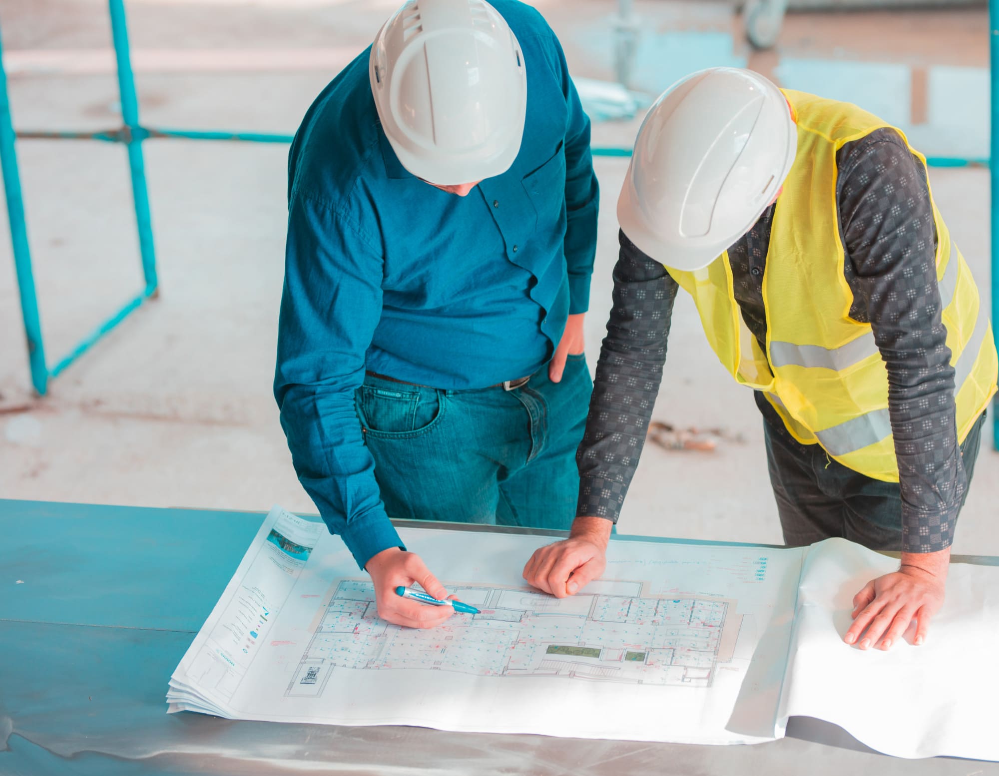 residential architecture Quebec showing construction managers wearing safety helmets and vest reviewing blueprints on site to supervise building progress.