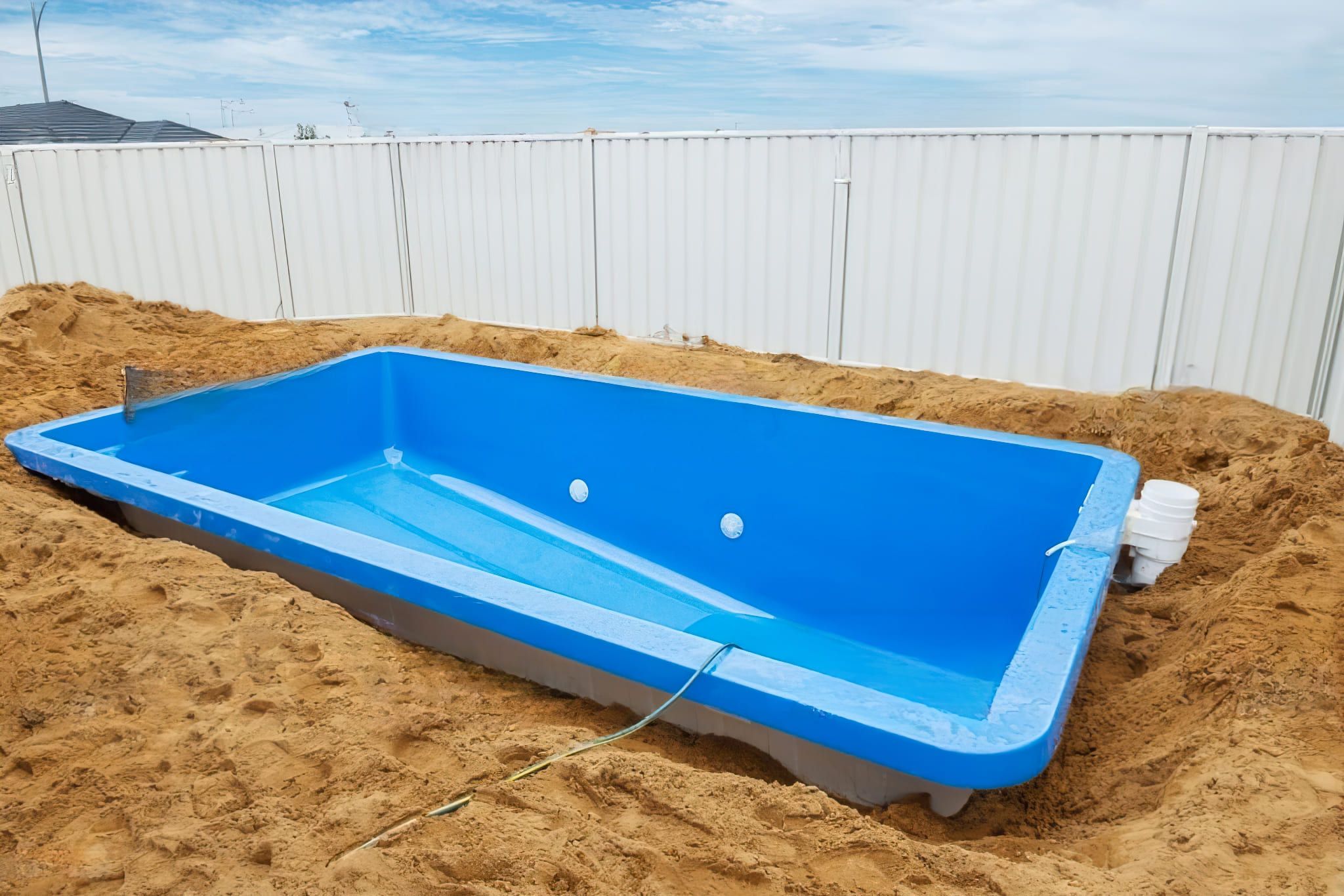 Swimming pools installation in Quebec — A prefabricated polyester swimming pool is being lowered into a prepared excavation. The fiberglass-reinforced (GFRP) pool shell is delivered in one piece, allowing for a faster and more efficient installation compared to traditional concrete pools.