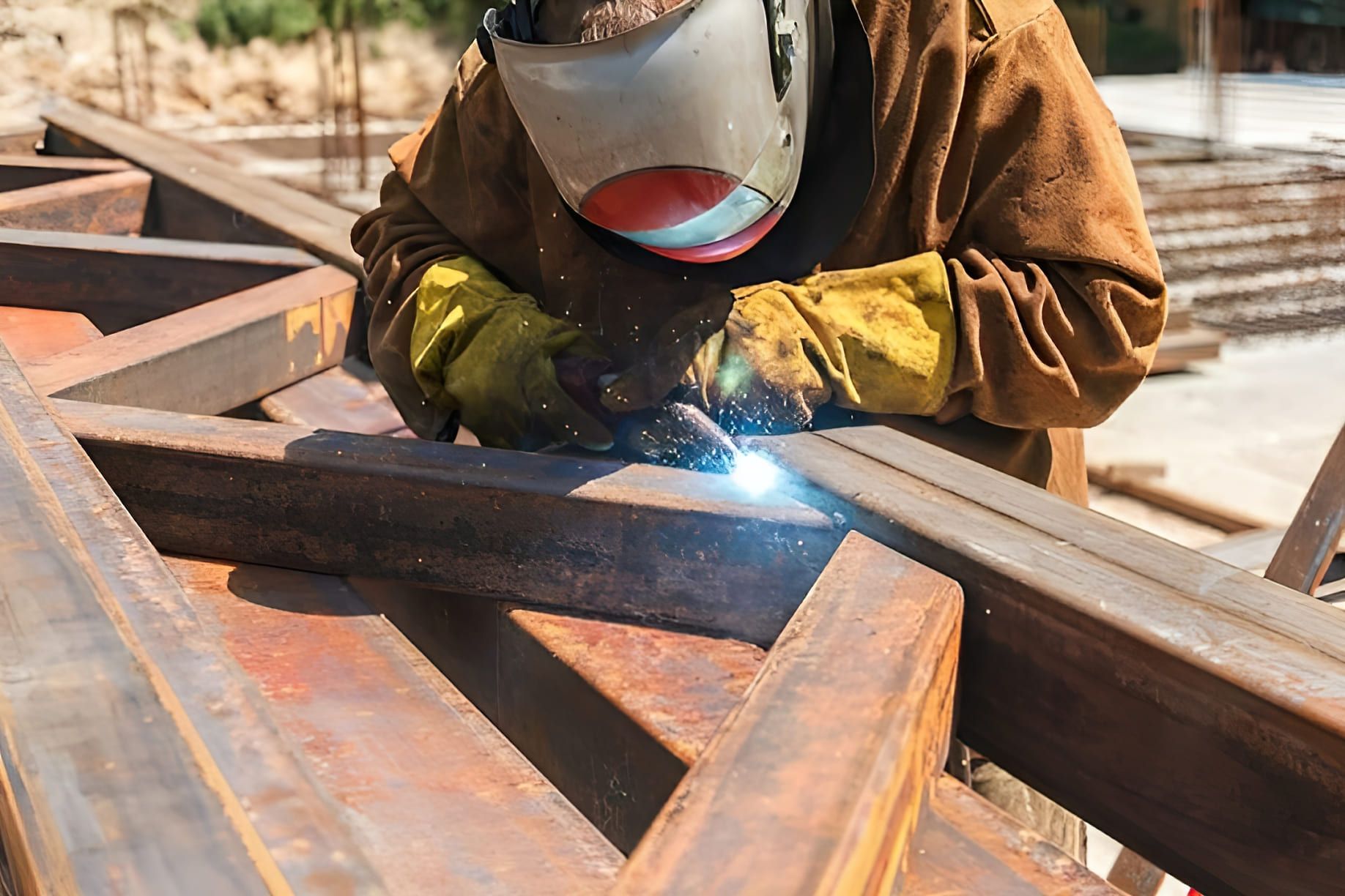 worker performing metal inert gas (MIG) or metal active gas (MAG) welding — the image shows a person welding metal components using a gas-shielded arc process, where a consumable wire electrode and protective gas create clean, strong welds; the process is common in metal fabrication and construction for its efficiency and high-quality results.