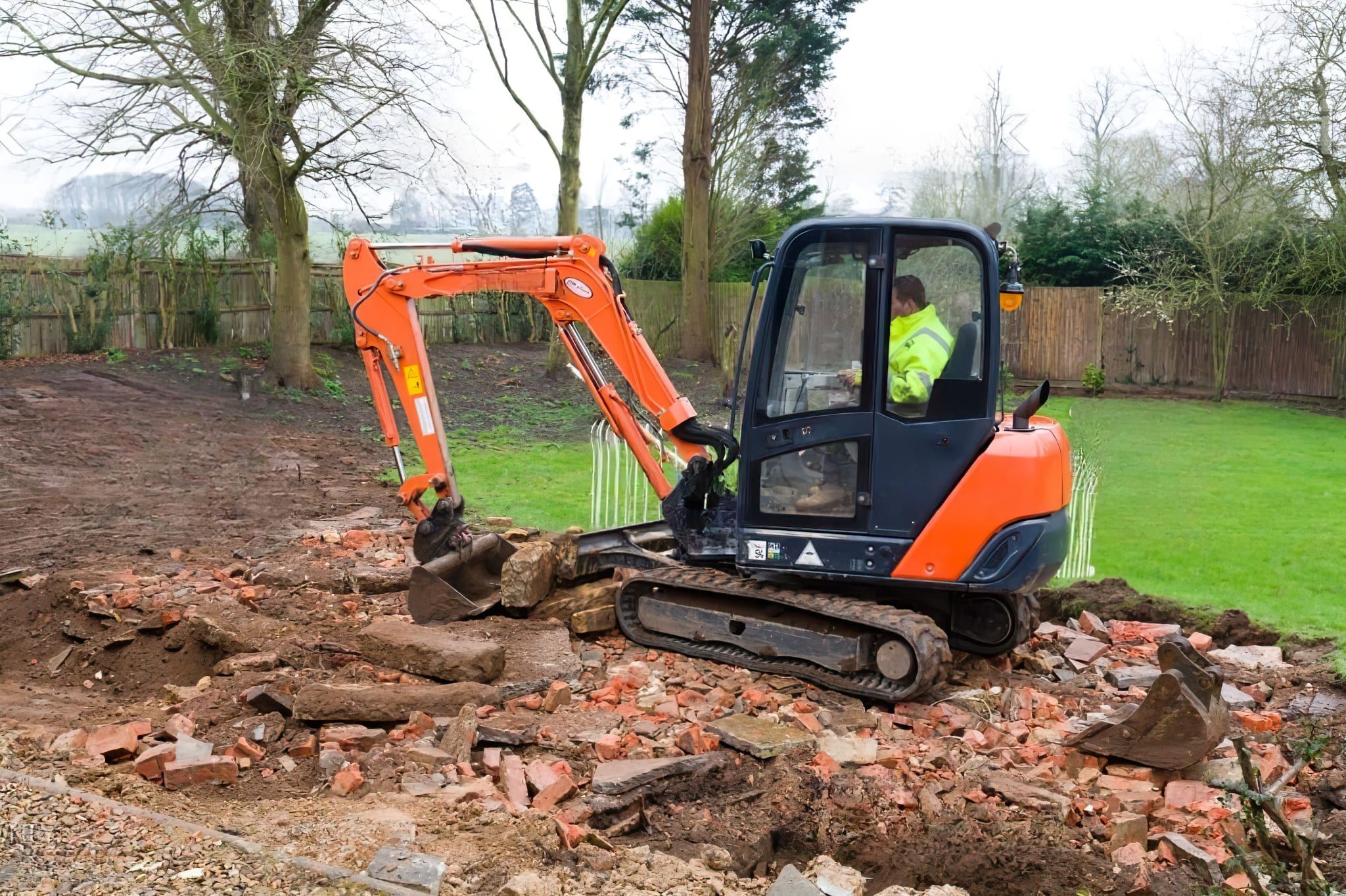 A compact mini excavator moving debris on a construction site in Quebec, used for digging, grading, and material handling in tight spaces as part of excavation or landscaping work.