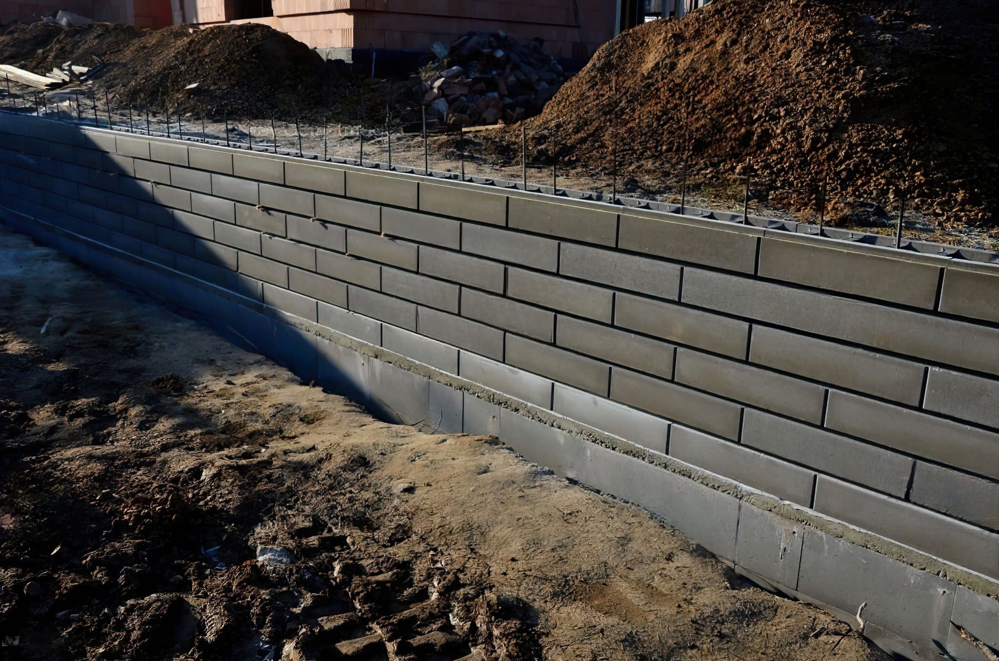 Concrete block retaining wall in Quebec used to hold back soil and prevent erosion, providing slope stabilization and level surfaces, built on a solid foundation for residential or landscape support.