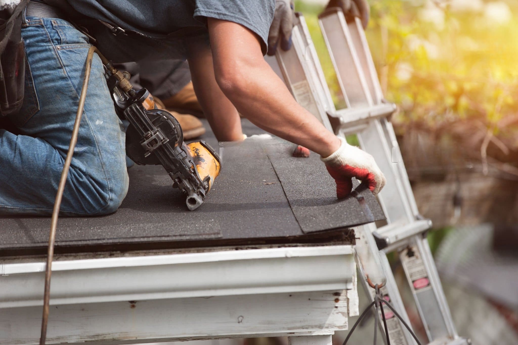 Roof installation in Quebec and Montreal showing roofers attaching shingles near a metal gutter system. The roof gutter collects and directs rainwater away from the building to prevent water damage and protect the foundation.