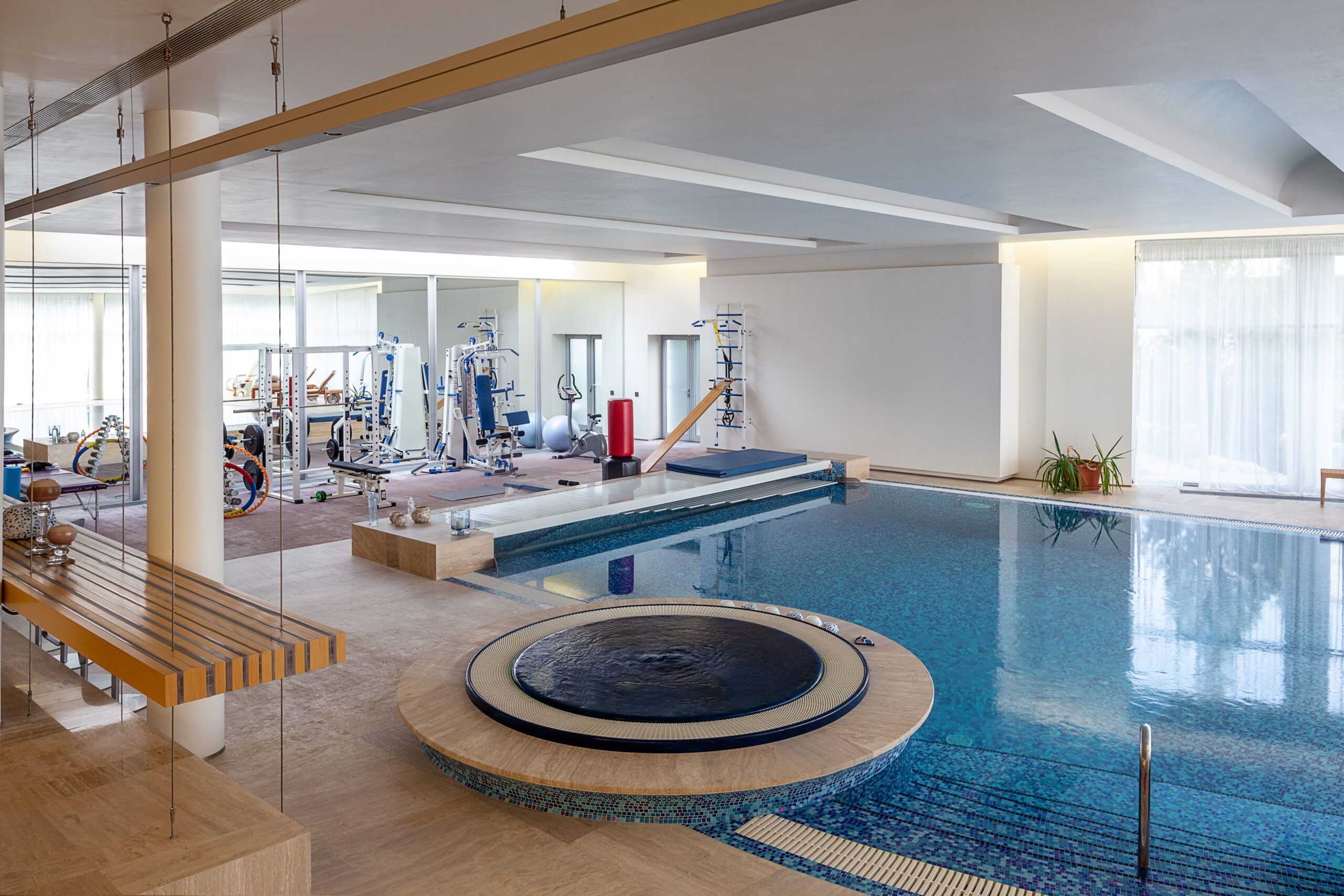 Residential swimming pools Quebec — luxurious indoor pool area integrated with a private home gym, featuring modern fitness equipment, a sleek swimming pool, and elegant lighting for a high-end residential design.