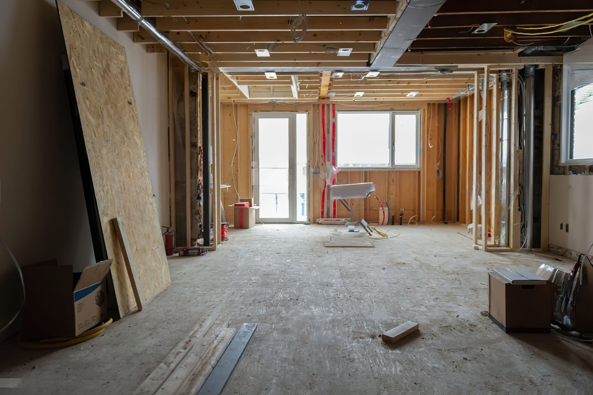 A residential house in Quebec undergoing structural modification, showing exposed wooden studs, partially open ceiling beams, and renovation materials on the floor.
