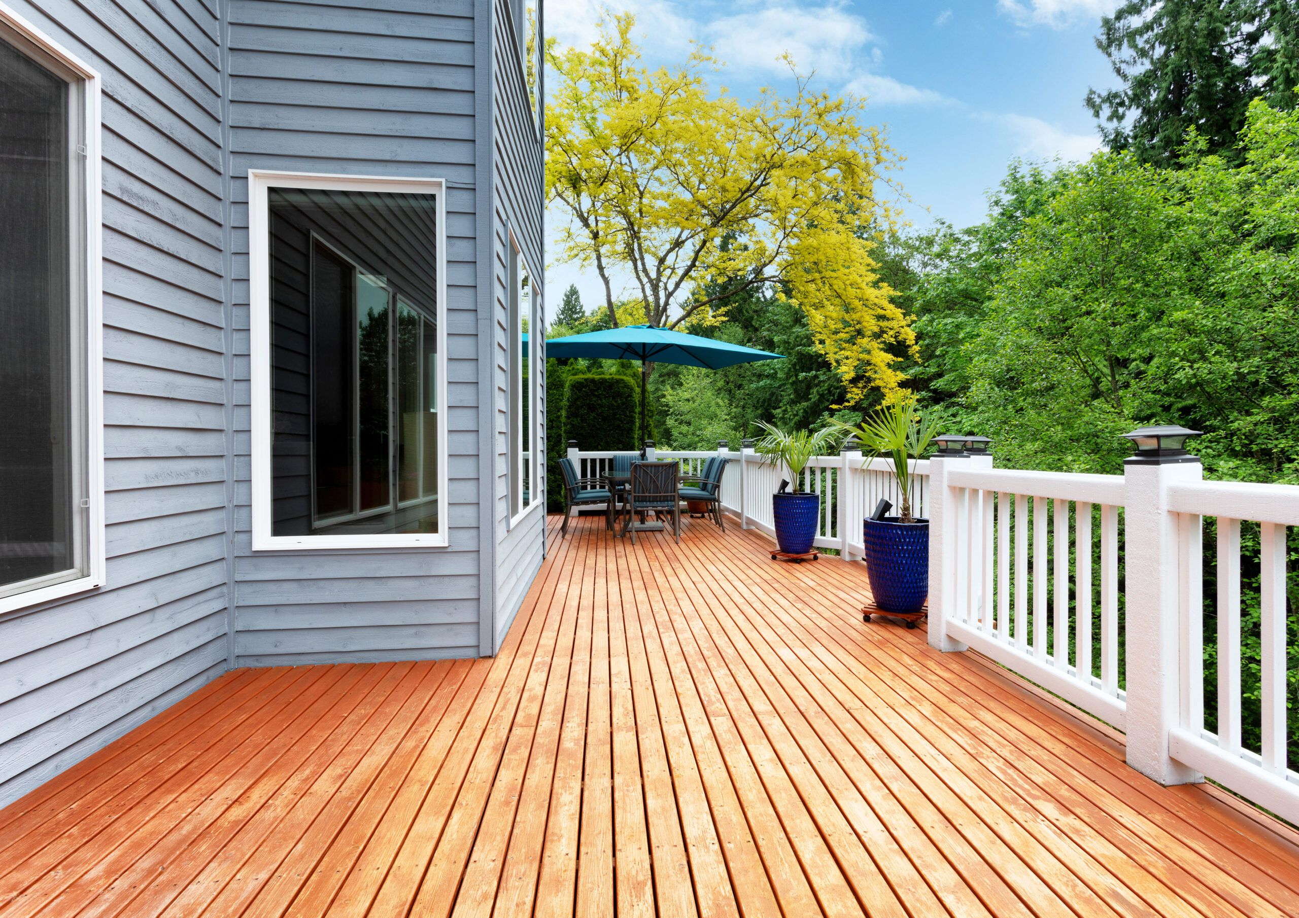 A wooden deck attached to a house, built with durable weather-resistant timber and designed as an inviting outdoor living space, commonly featured in garden fences and landscaping projects across Quebec.
