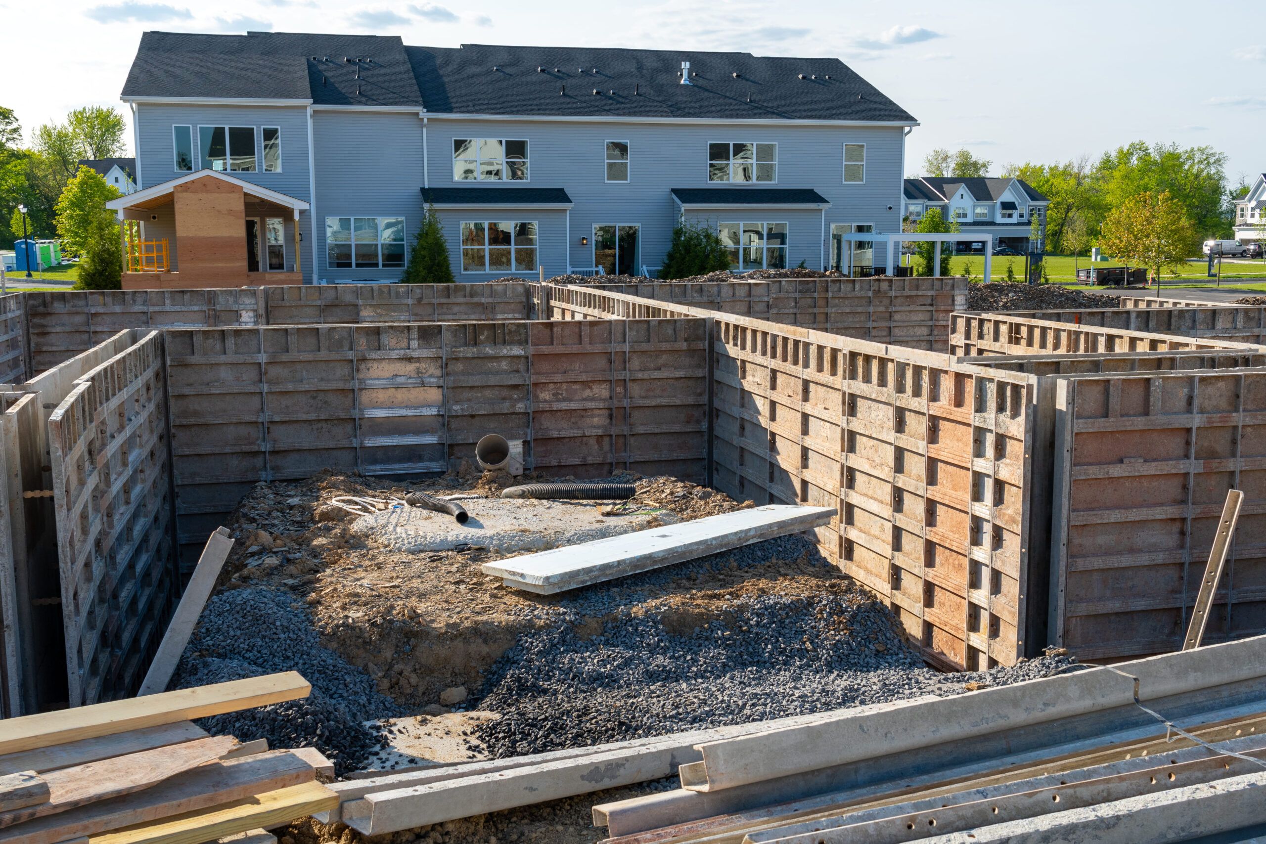 Residential construction site in Quebec showing concrete formwork for basement and foundation walls, with steel reinforcement inside the forms, preparing for the pouring of reinforced concrete to create durable load-bearing structures.