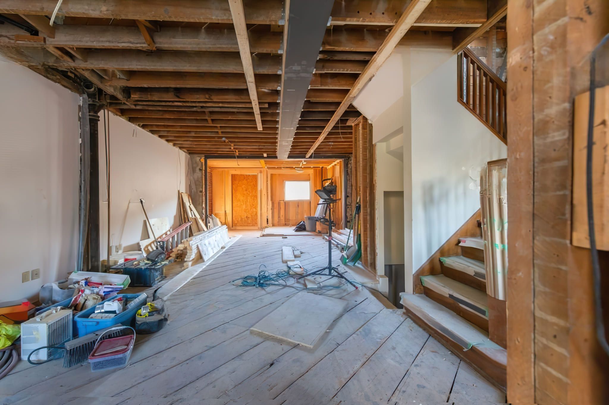 A residential interior in Montreal undergoing structural modification, showing exposed ceiling beams and wall studs during renovation work.
