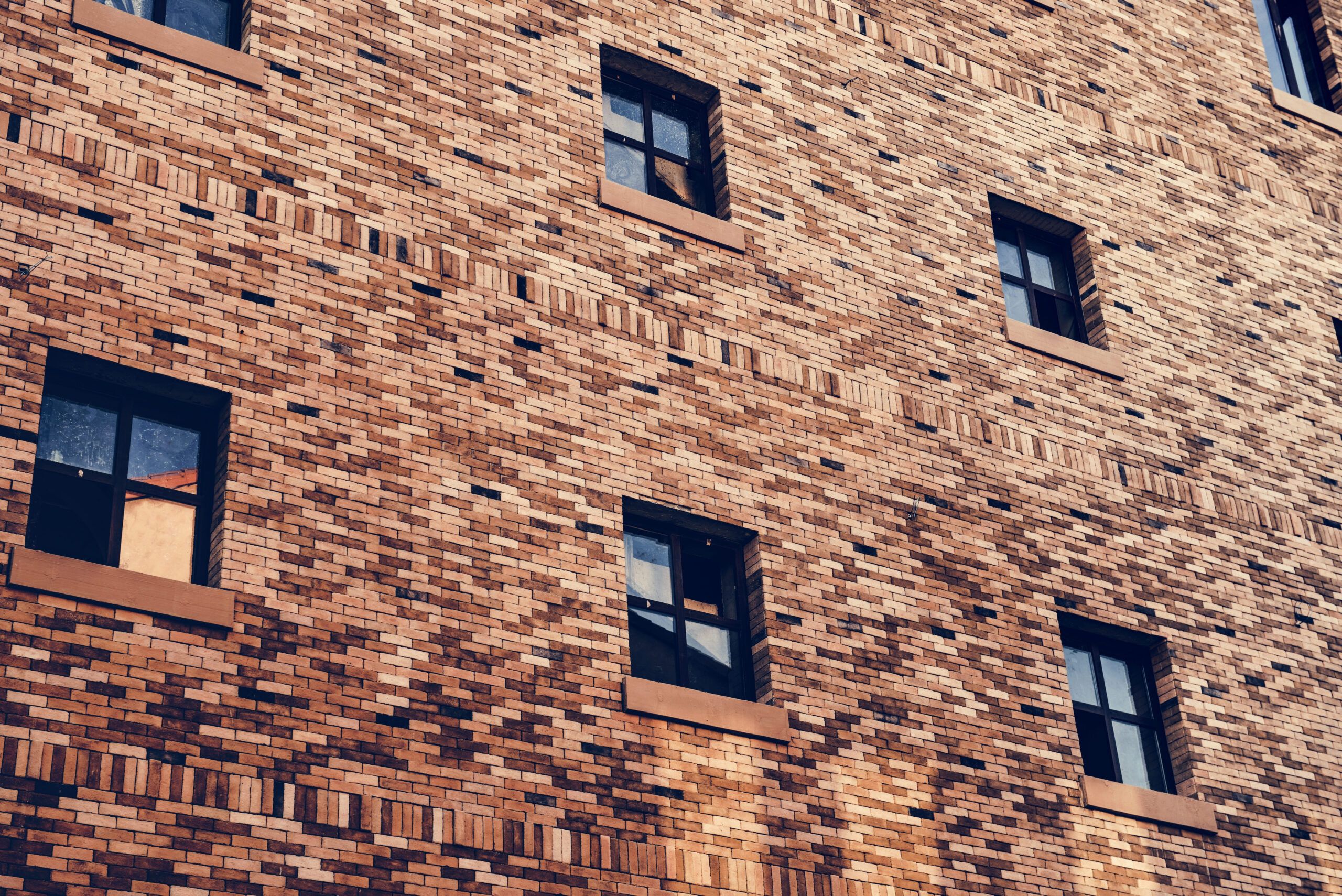Brick façade of a modern building with multiple windows, representing exterior cladding services in Montreal that enhance both the durability and aesthetic appeal of building exteriors.