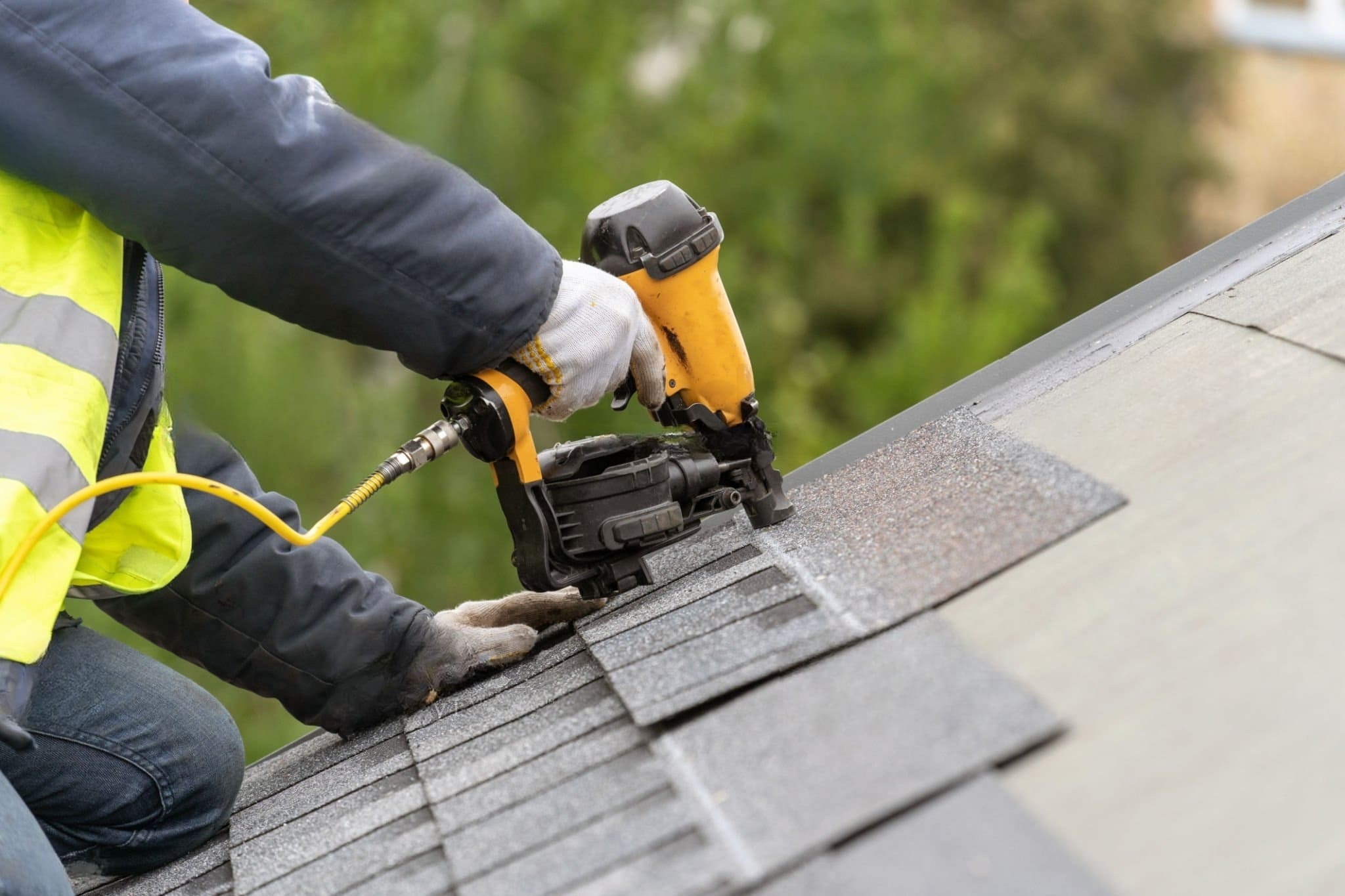 A roof repair in Quebec showing a worker using a nail gun to attach shingles. The process involves replacing damaged materials, inspecting the roof deck, and securing new shingles to extend the roof’s lifespan.