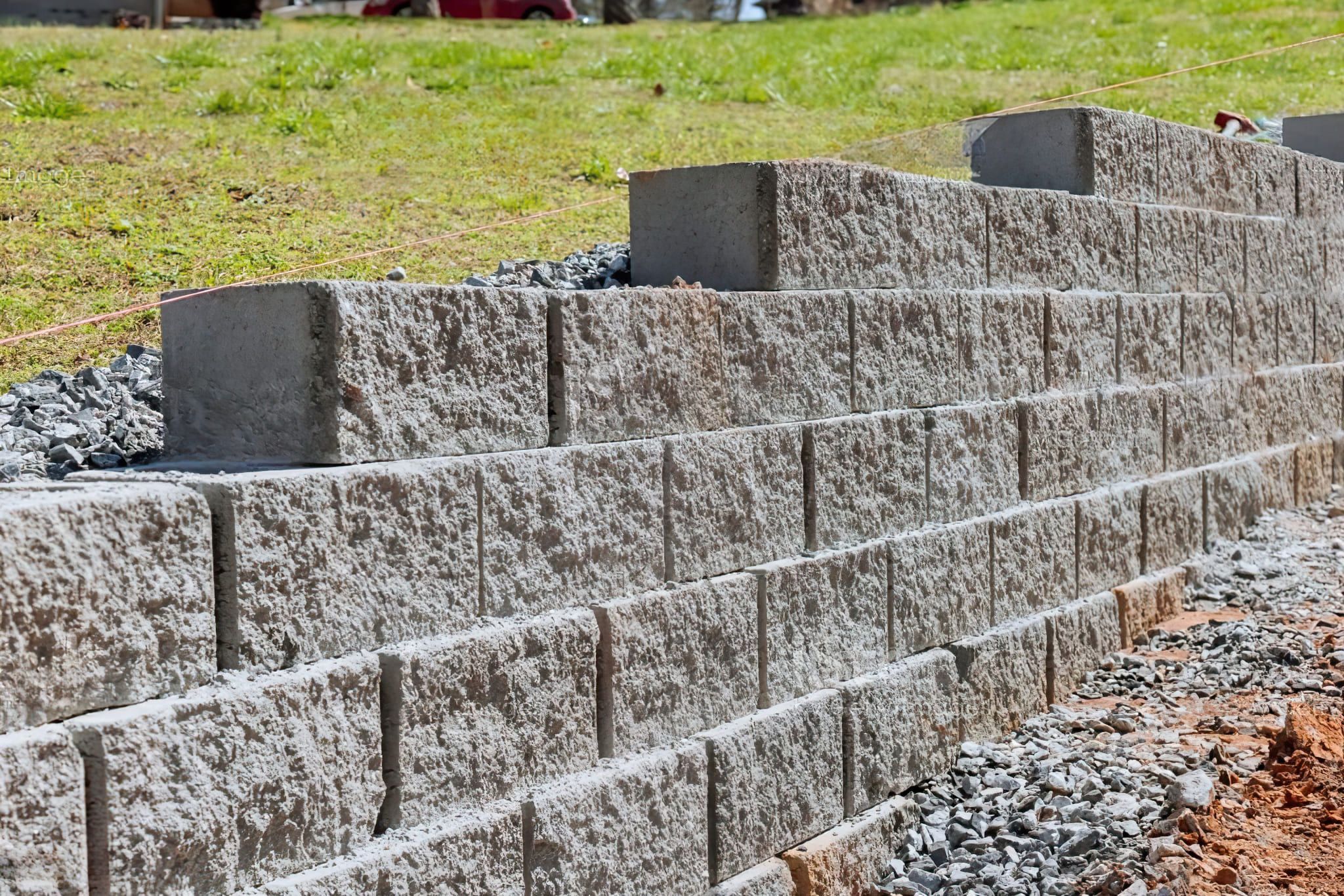 Backyard retaining wall in Quebec built with L-shaped concrete blocks (L-stones) used for stabilizing slopes and creating level areas in landscaping projects.