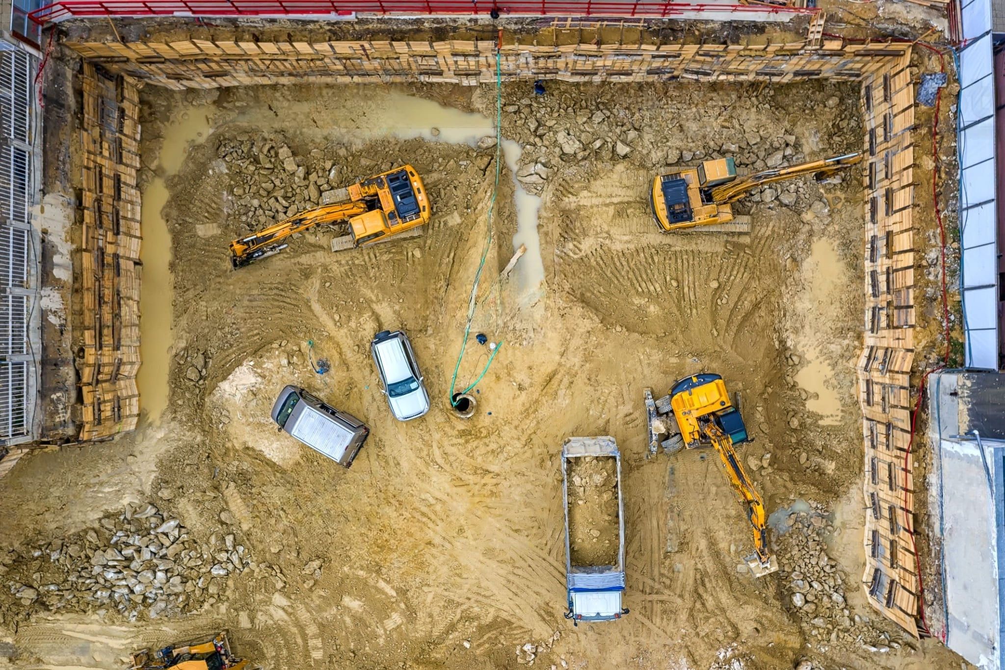 Excavation services in Montreal captured on a construction site with excavators and trucks performing earthmoving and foundation work, featuring secured trench walls and strict safety measures for efficient site preparation.