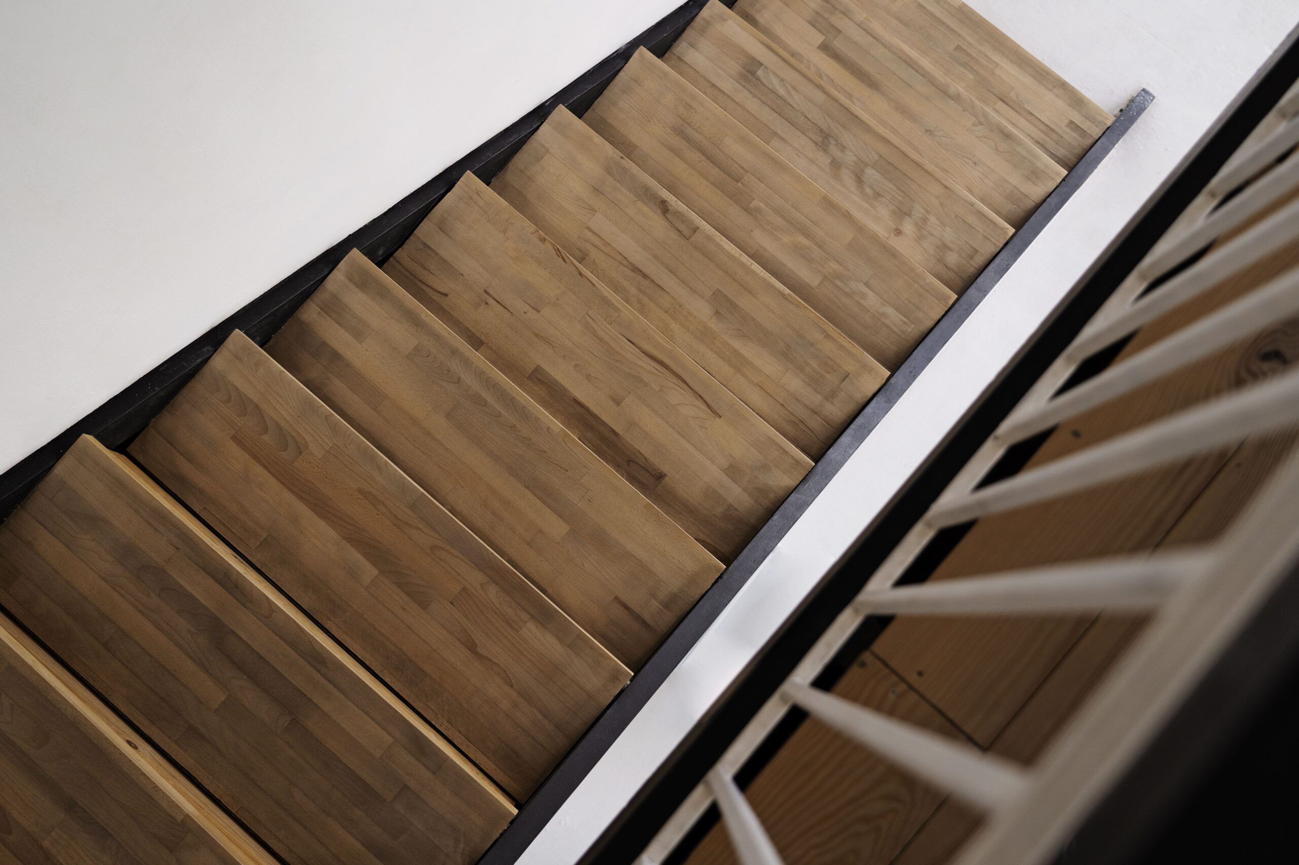 Staircase installation in Montreal showing a space-saving curved wooden staircase with a central support beam, combining functionality and modern design for residential interiors.
