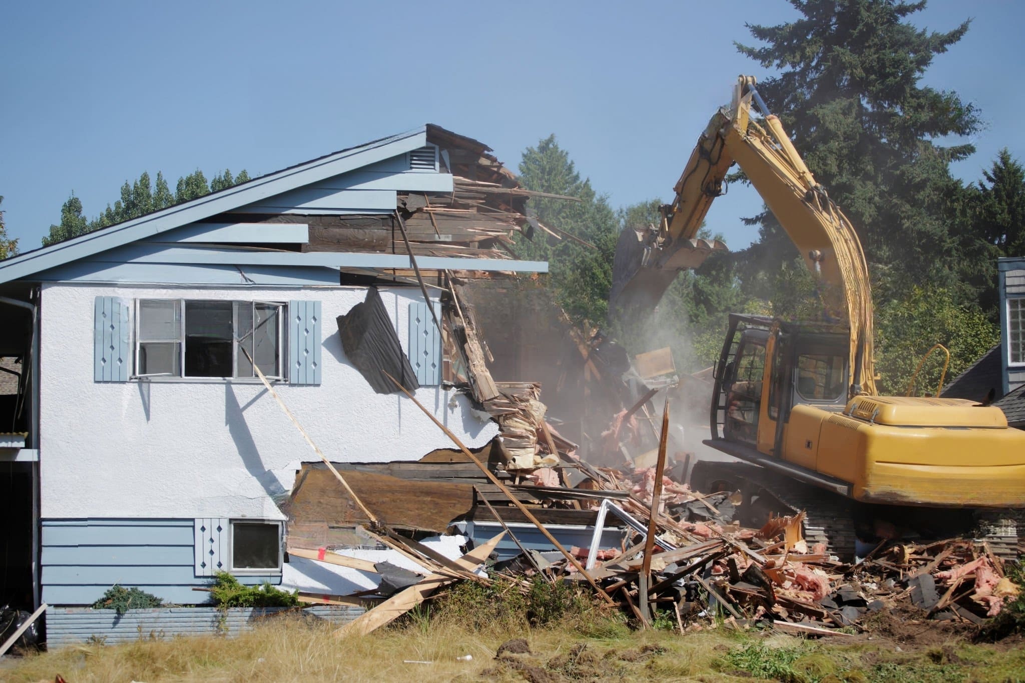Residential Demolition Montreal with an excavator tearing down a house, illustrating the safe and controlled removal of old or damaged residential structures before redevelopment.