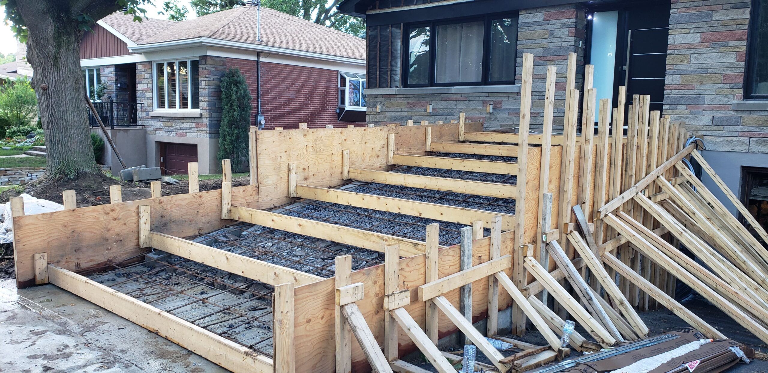 Exterior stairs installation Montreal showing an on-site concrete staircase being poured with a wooden formwork and visible steel reinforcement for structural stability.