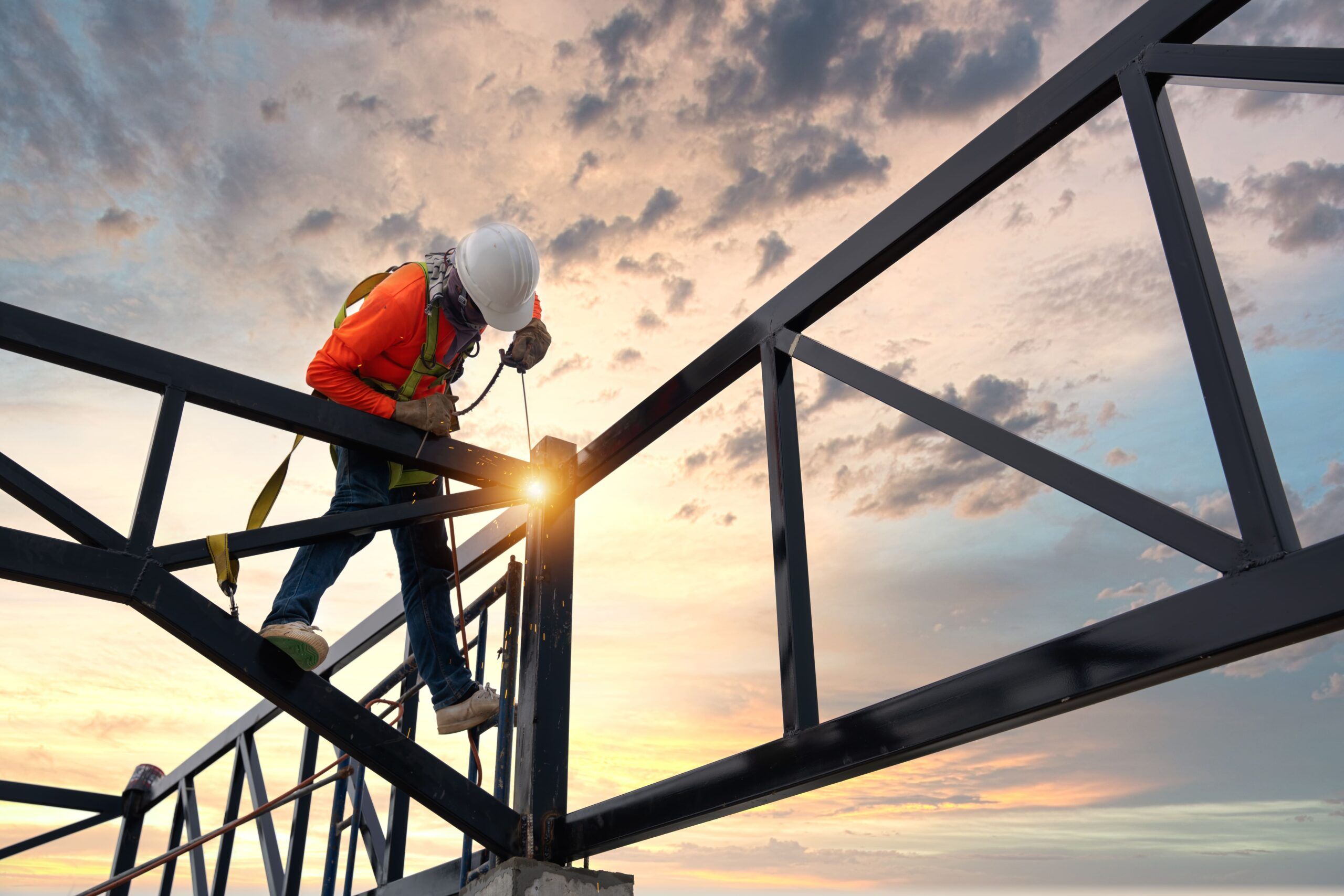 construction worker welding a steel structure in Quebec — the image shows a welder joining metal beams using high heat, wearing full protective gear; welding is essential in building projects such as bridges, industrial facilities, and structures, ensuring strong and safe metal connections on construction sites.