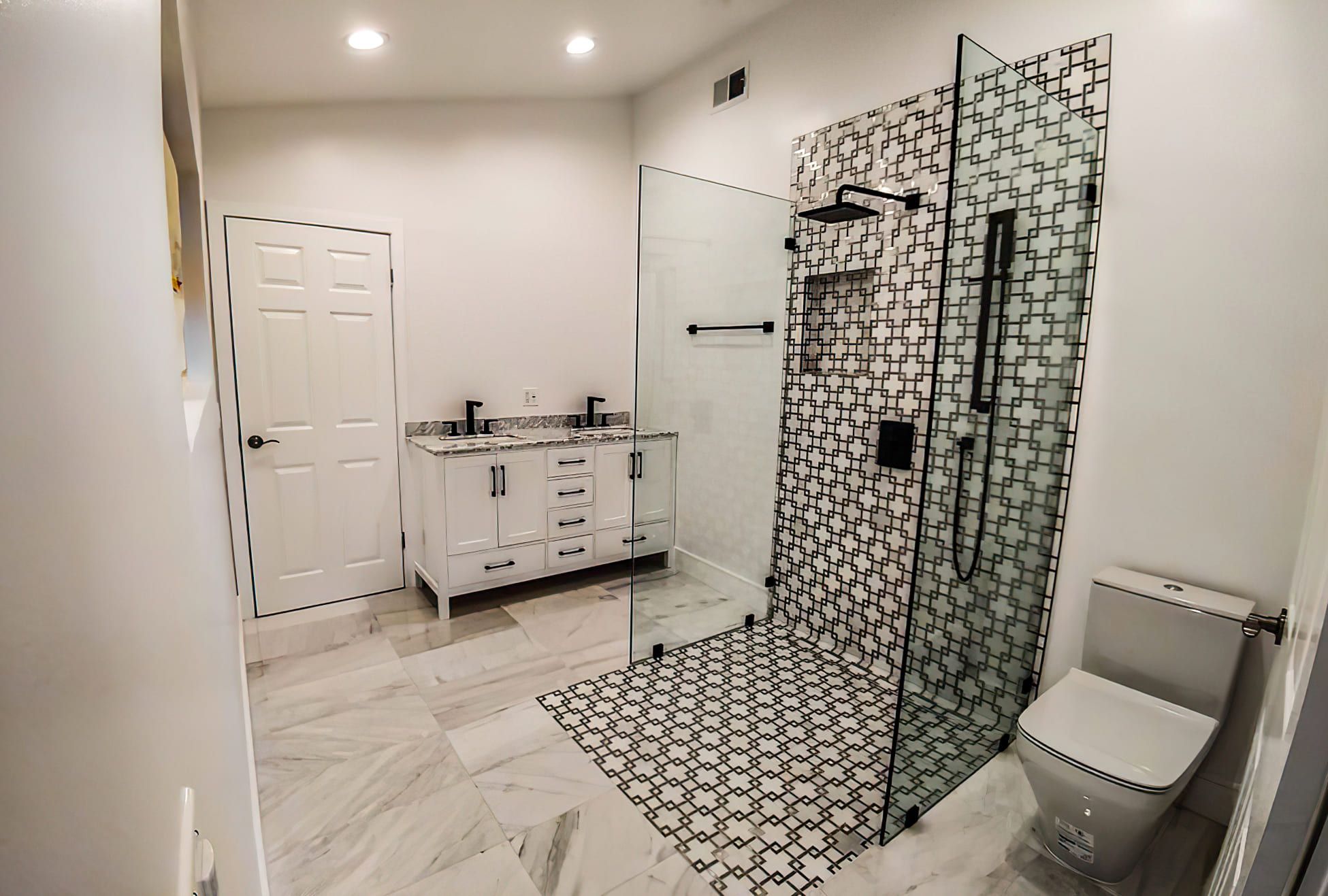 Modern bathroom with double vanity, glass walk-in shower, black fixtures, and geometric black-and-white tiles, showcasing elegant bathroom design and remodeling in Quebec with a luxurious marble floor.