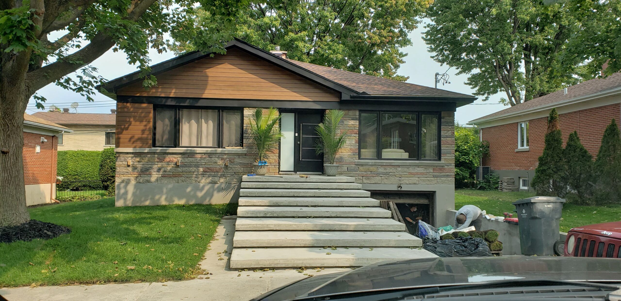 Staircases installation Quebec and Montreal showing an exterior home renovation by HMA Groupe Construction, featuring a modernized facade with stone and wood cladding and a newly installed staircase.