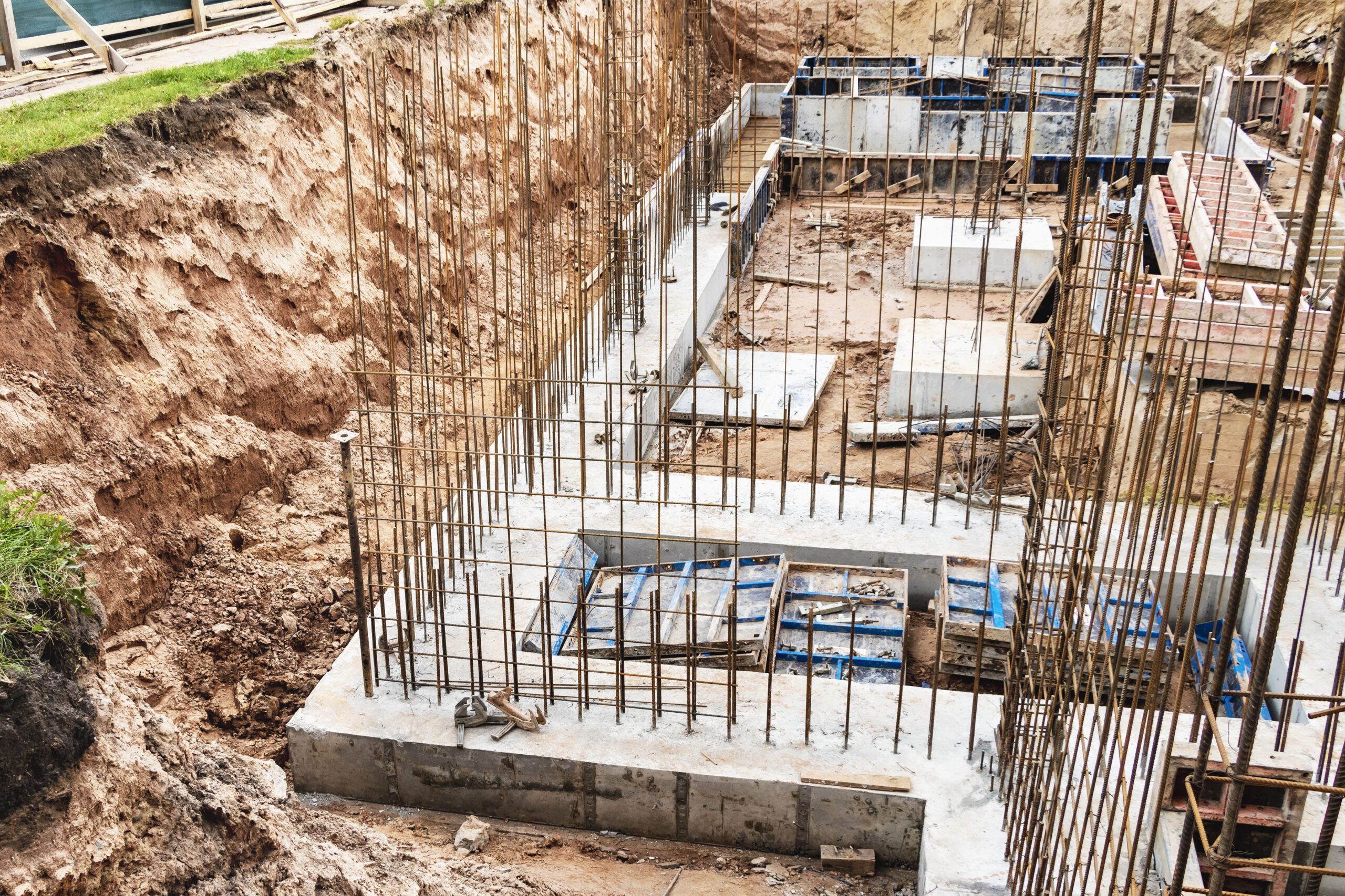 Foundation installation in Montreal showing a reinforced concrete slab with visible steel rebar, formwork, gravel base, and moisture barrier, forming the base structure for a residential building.