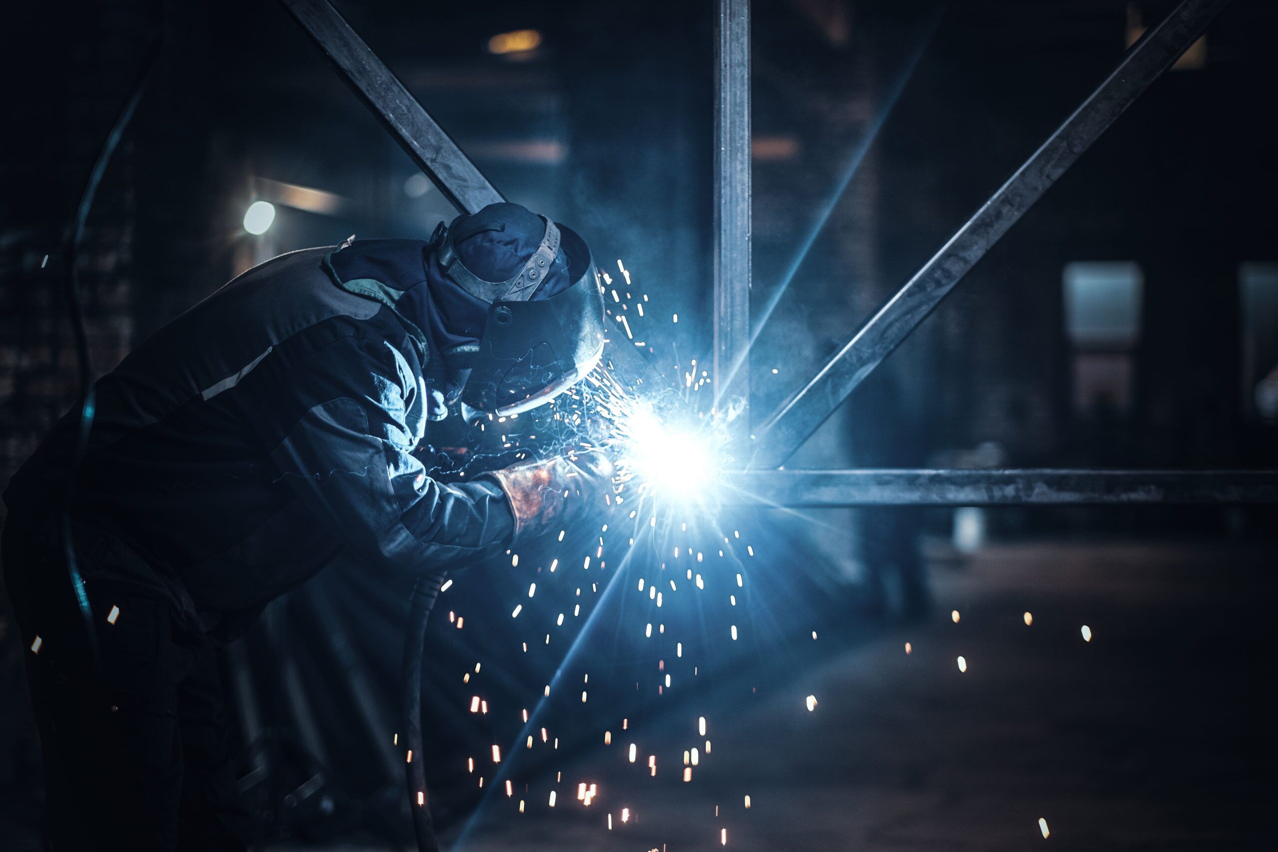 A welder wearing protective gear using an electric arc to join metal parts, showing skilled craftsmanship provided by Welding Services in Quebec and Montreal.