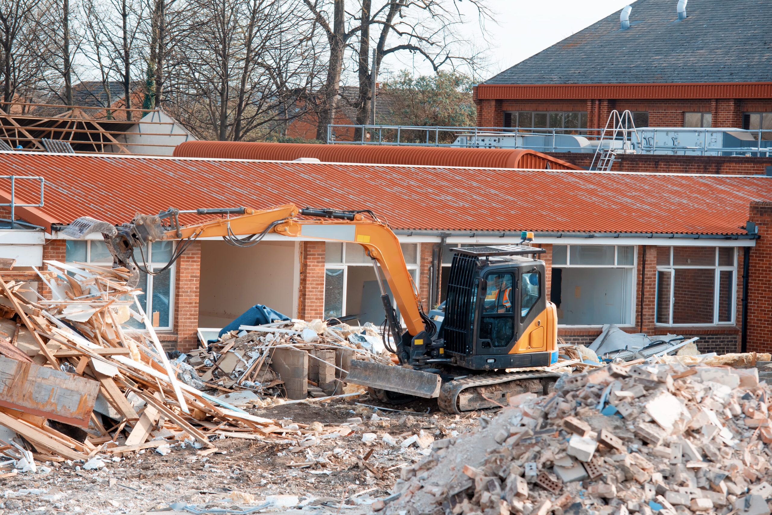 Demolition Services Quebec showing an excavator clearing debris from a partially dismantled building, illustrating professional structure removal and safe site preparation for future construction projects.
