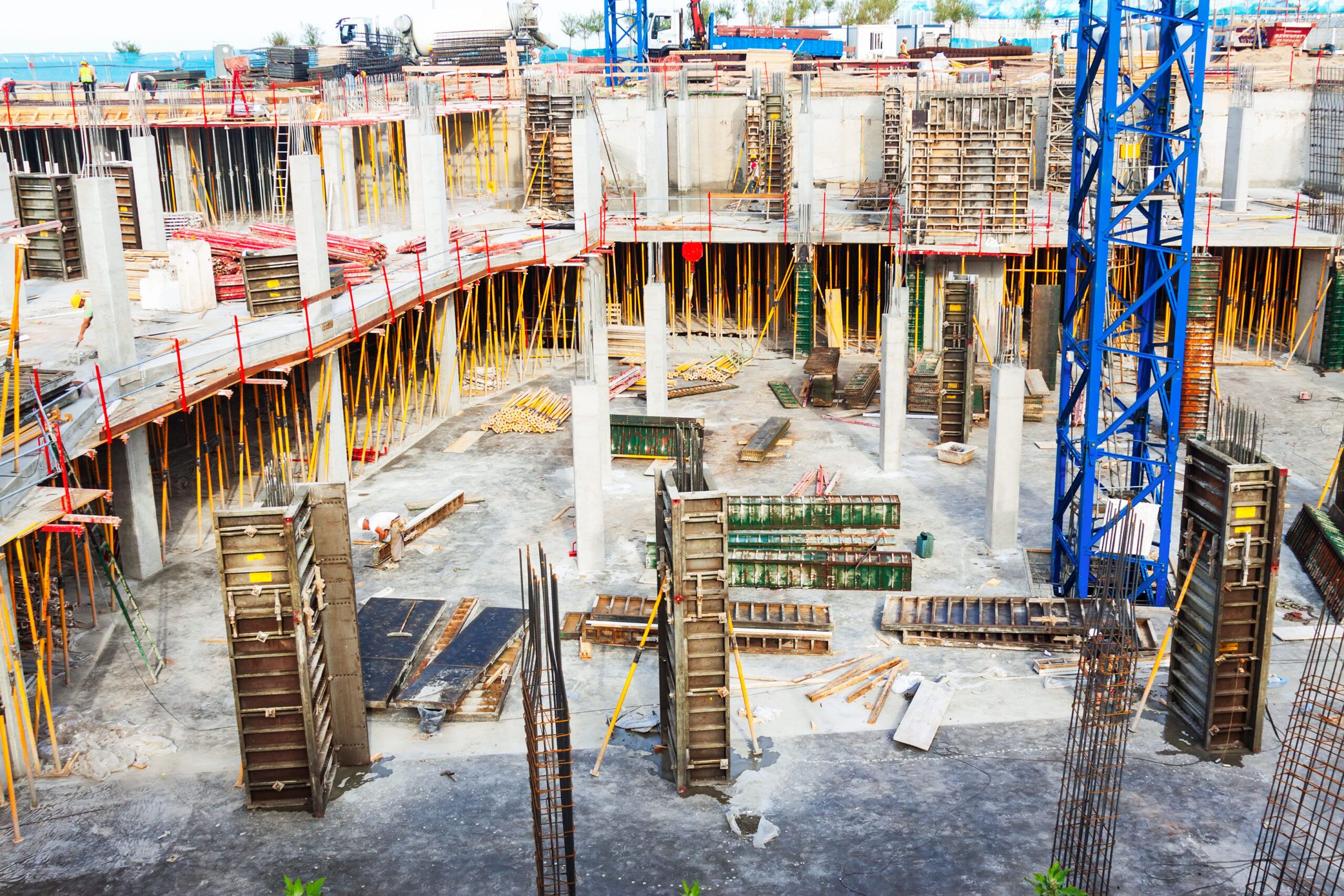 Concrete foundation construction site in Quebec showing reinforced concrete columns and walls with visible formwork, steel reinforcement bars, and adjustable ceiling supports used during the curing process.