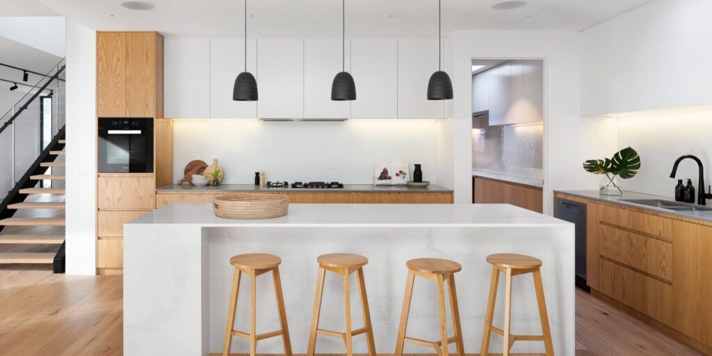 Modern kitchen with island, staircase, and underfloor heating system, showcasing energy-efficient comfort and elegant design as part of kitchen and bathrooms renovation in Quebec.