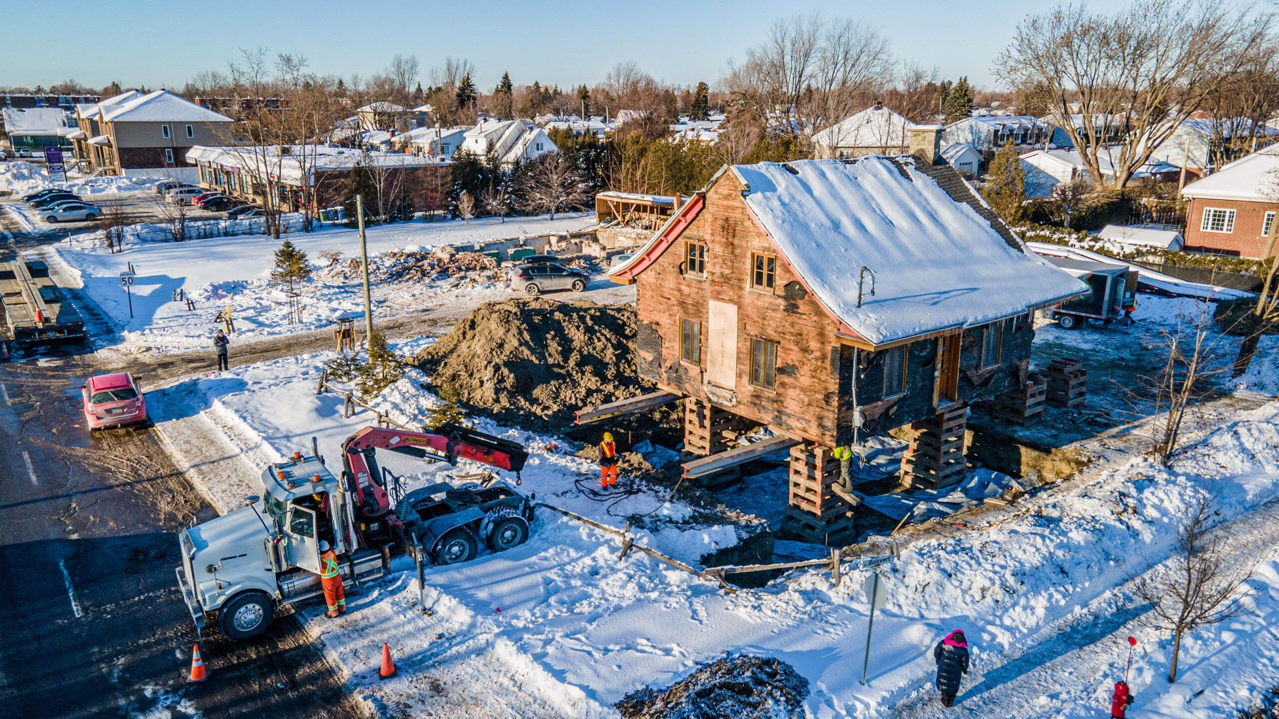 residential building lift Quebec showing historic wooden house from the 19th century being relocated on a flatbed truck in Saint-Jean-sur-Richelieu, Quebec, during a planned move for restoration and redevelopment.