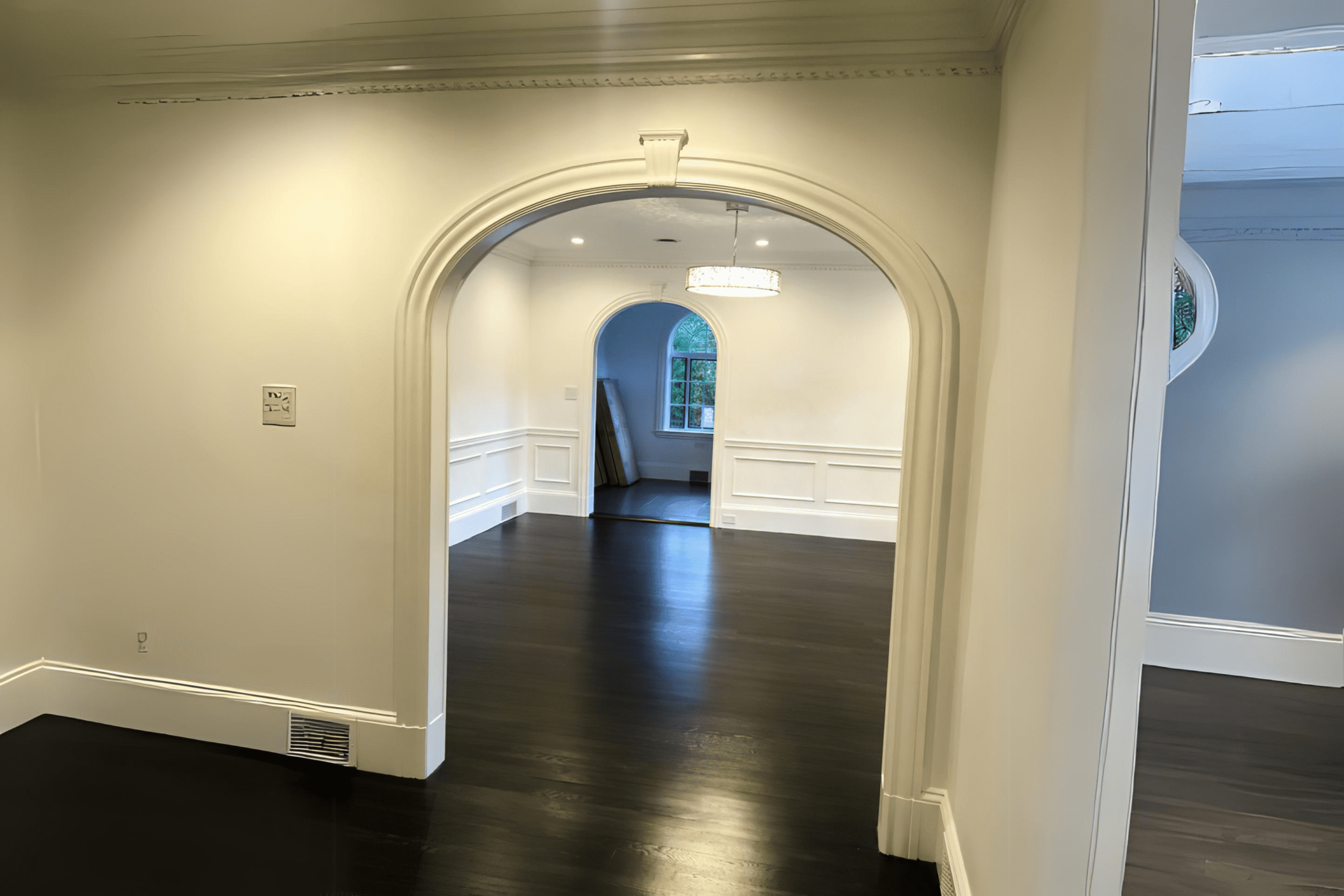An interior archway connecting two freshly painted rooms, showcasing smooth wall finishes and clean lines as part of professional painting services in Montreal.